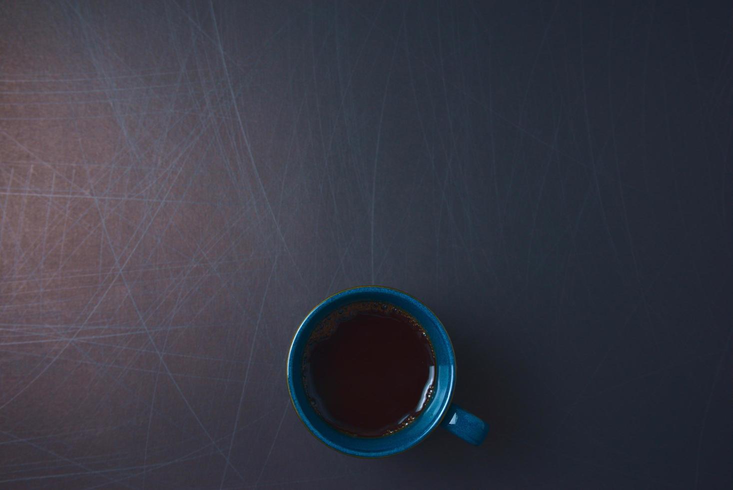 blauwe ceramische kop zwarte hete koffie op gekraste achtergrond. foto