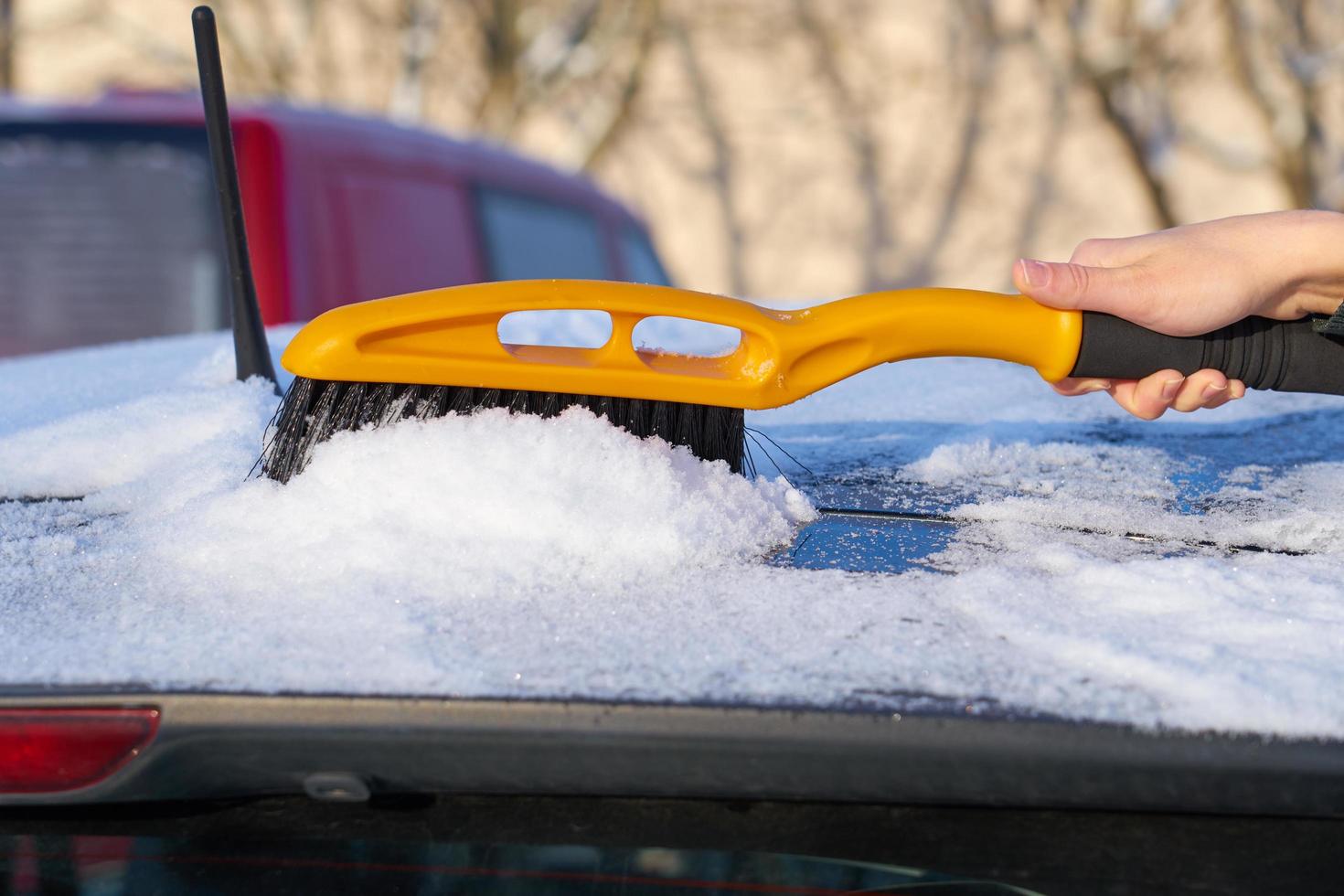 sneeuw verwijderen van het dak van een auto foto