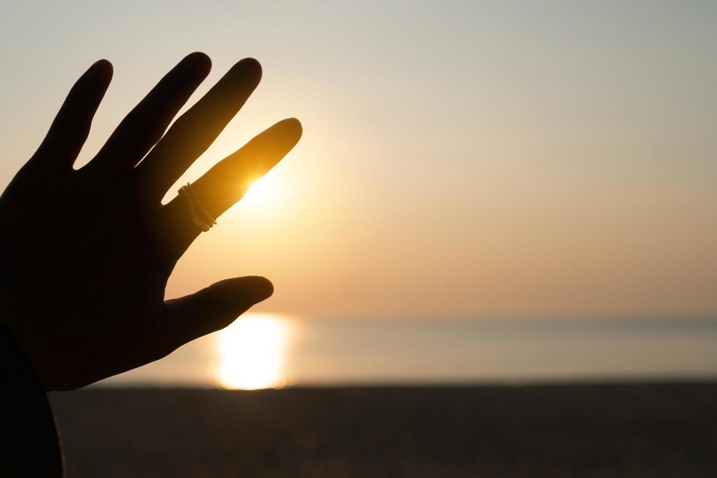 hand reiken naar een zonsondergang hemel strand zand natuur achtergrond foto