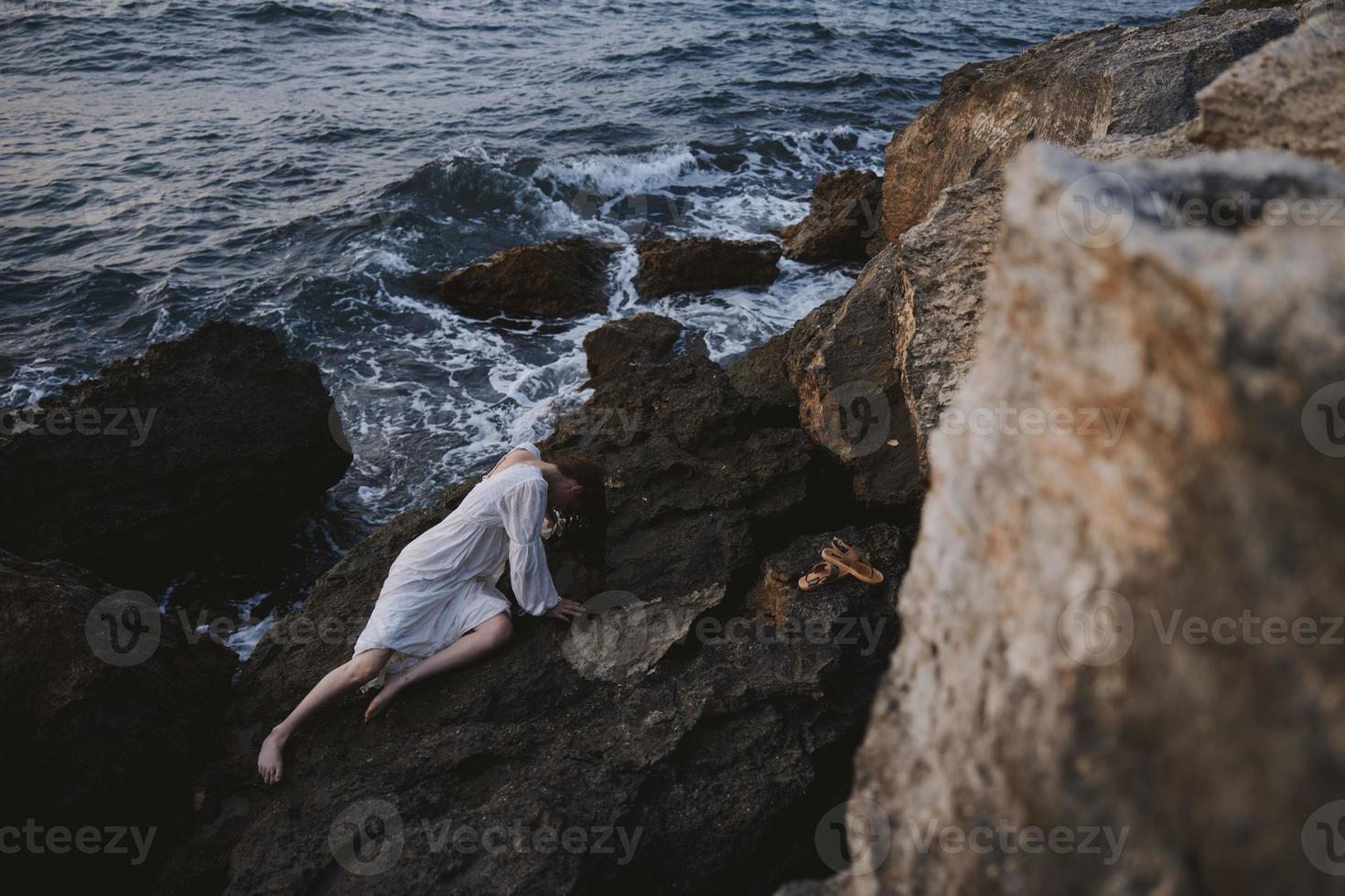mooi bruid aan het liegen Aan rotsachtig kust met scheuren Aan rotsachtig oppervlakte visie van bovenstaand foto
