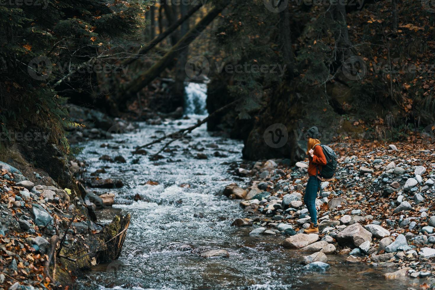 reiziger met rugzak landschap bergen transparant rivier- vijver en Woud in de achtergrond foto