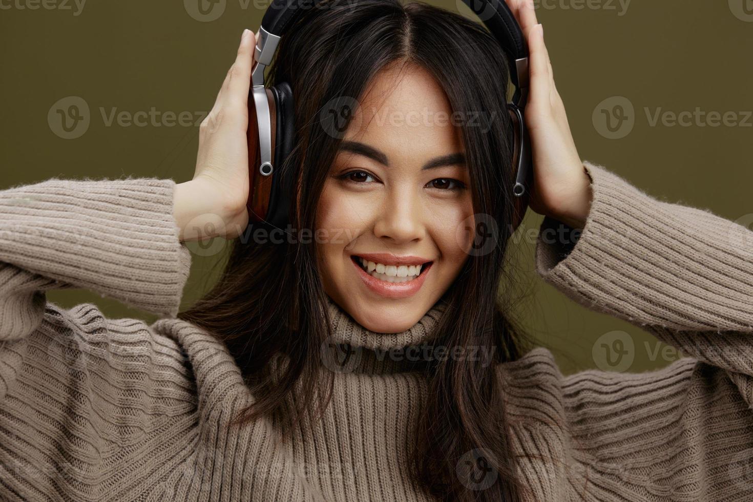jong vrouw in een trui luisteren naar muziek- met hoofdtelefoons pret groen achtergrond foto
