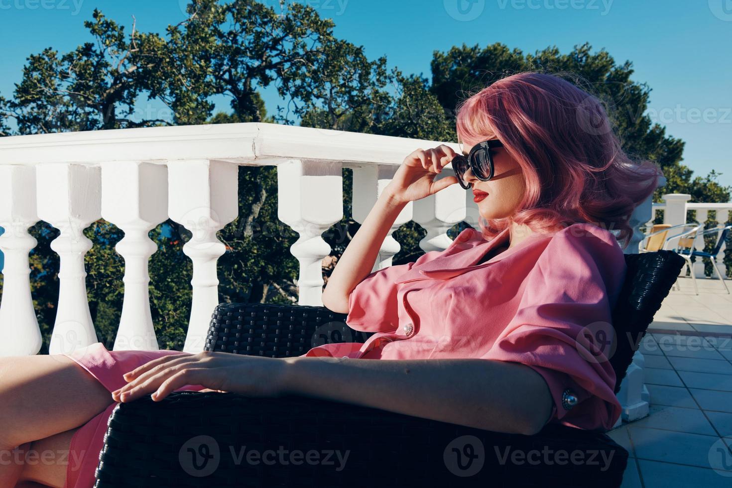 portret van een jong mooi vrouw roze jurk zit Aan de terras zonnig dag foto