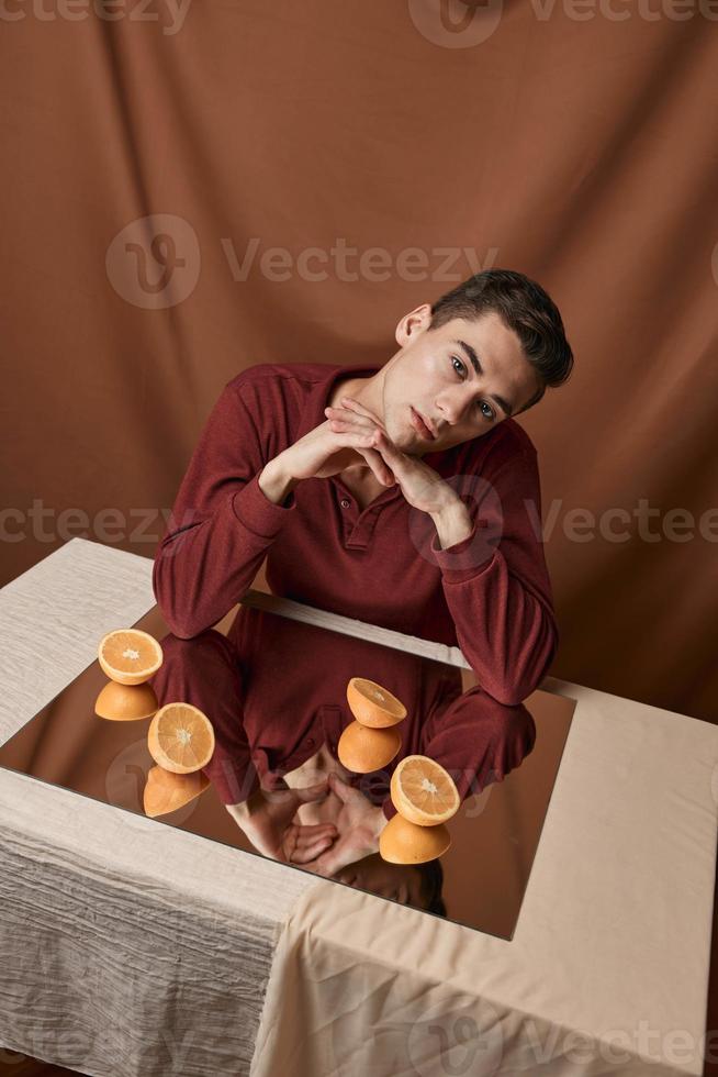 vent Bij de tafel met een spiegel en sinaasappels Aan een kleding stof achtergrond foto