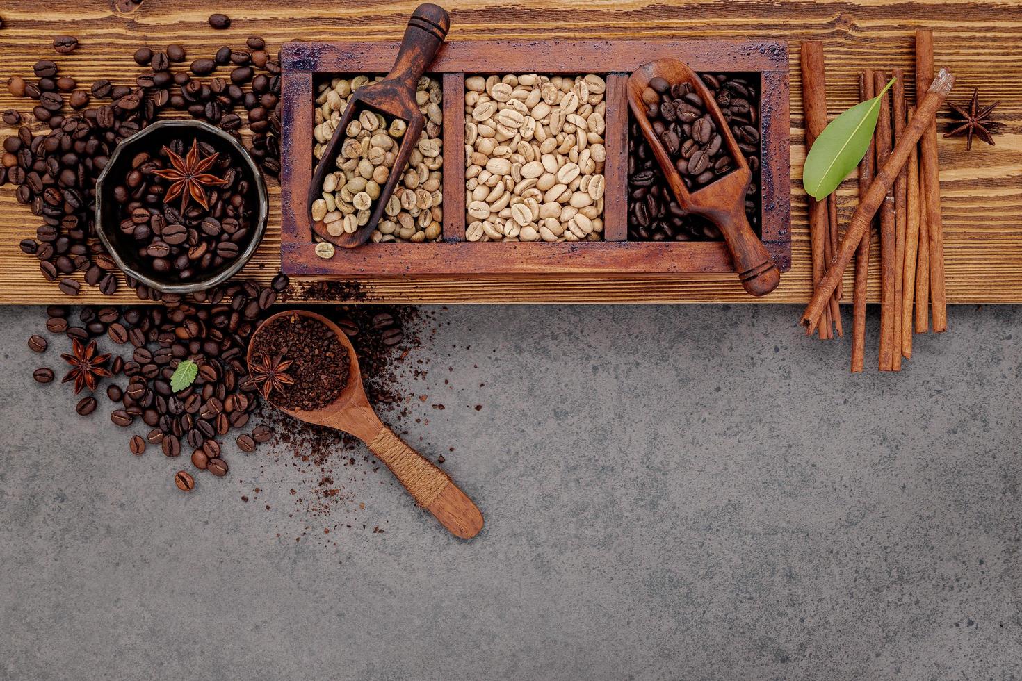 verschillende gebrande koffiebonen in een houten doos met een handmatige koffiemolen setup op een armoedige houten achtergrond. foto