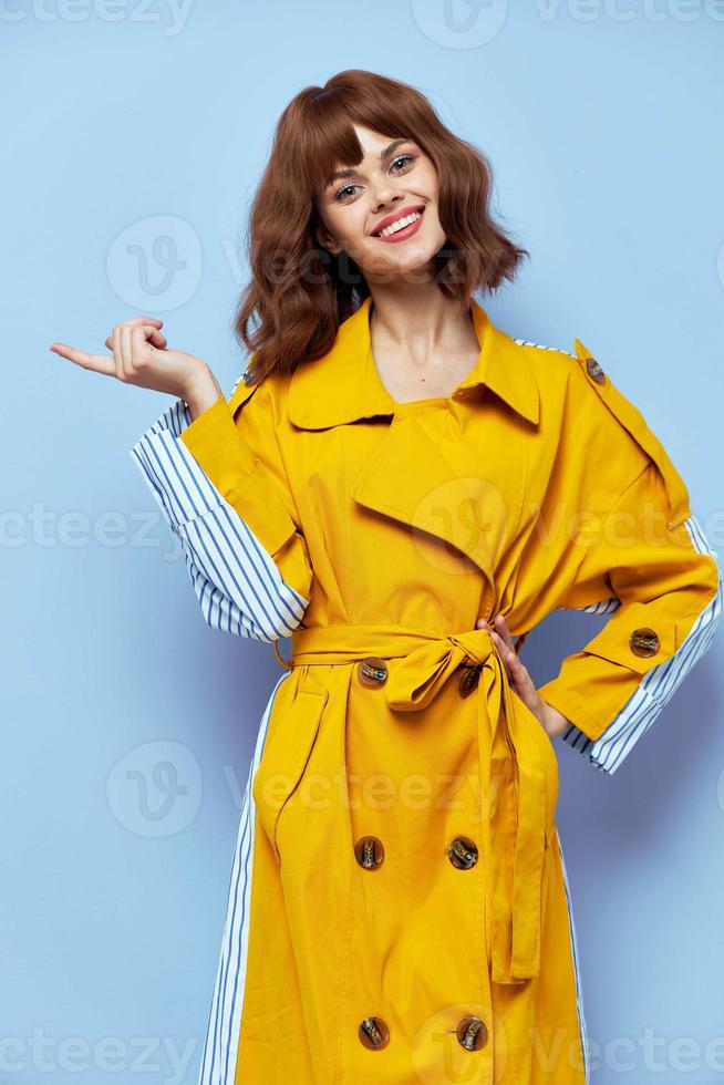 meisje in een modieus jas met toetsen shows haar vinger naar de kant Aan een blauw achtergrond foto