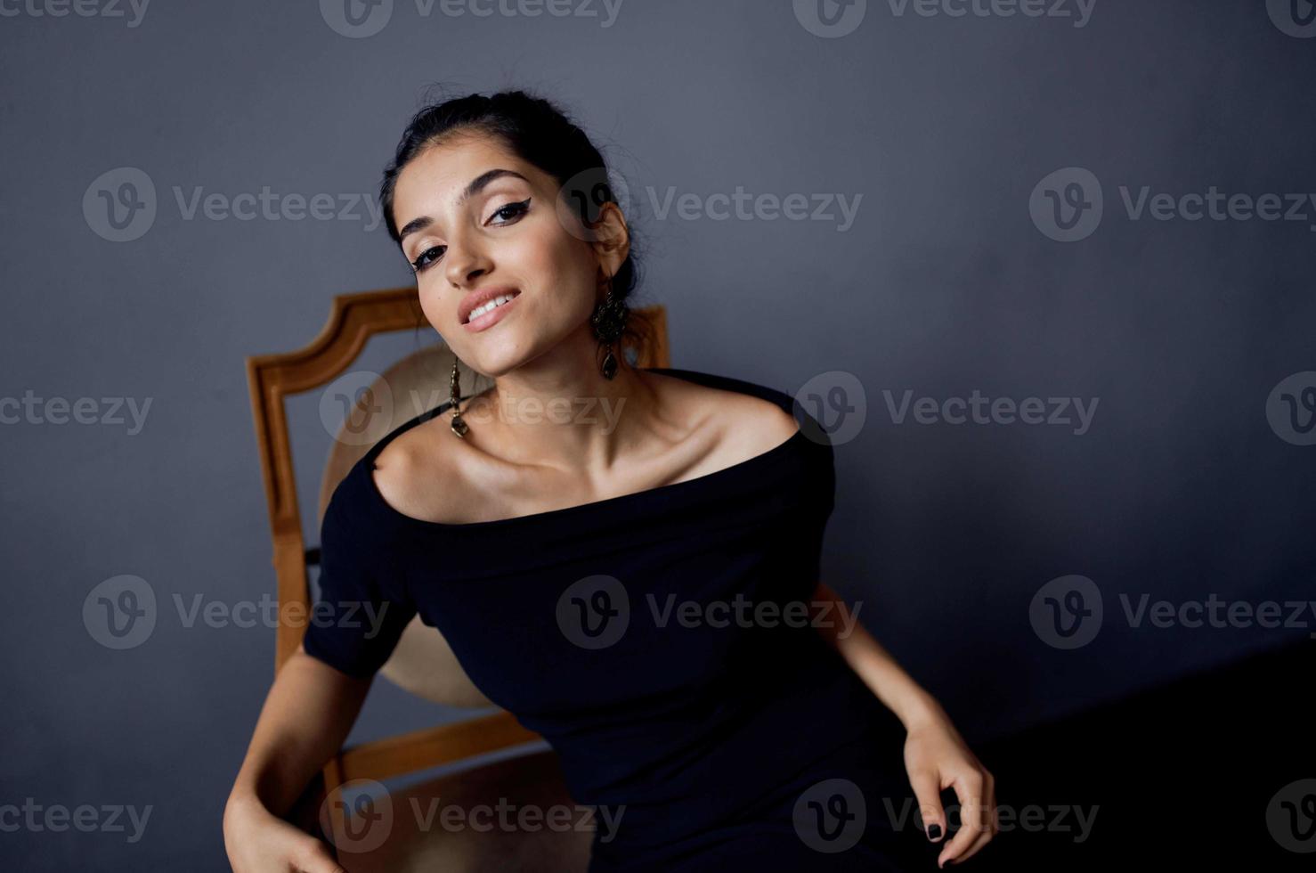 mooi vrouw in een zwart jurk in de buurt de stoel luxe mode levensstijl studio foto