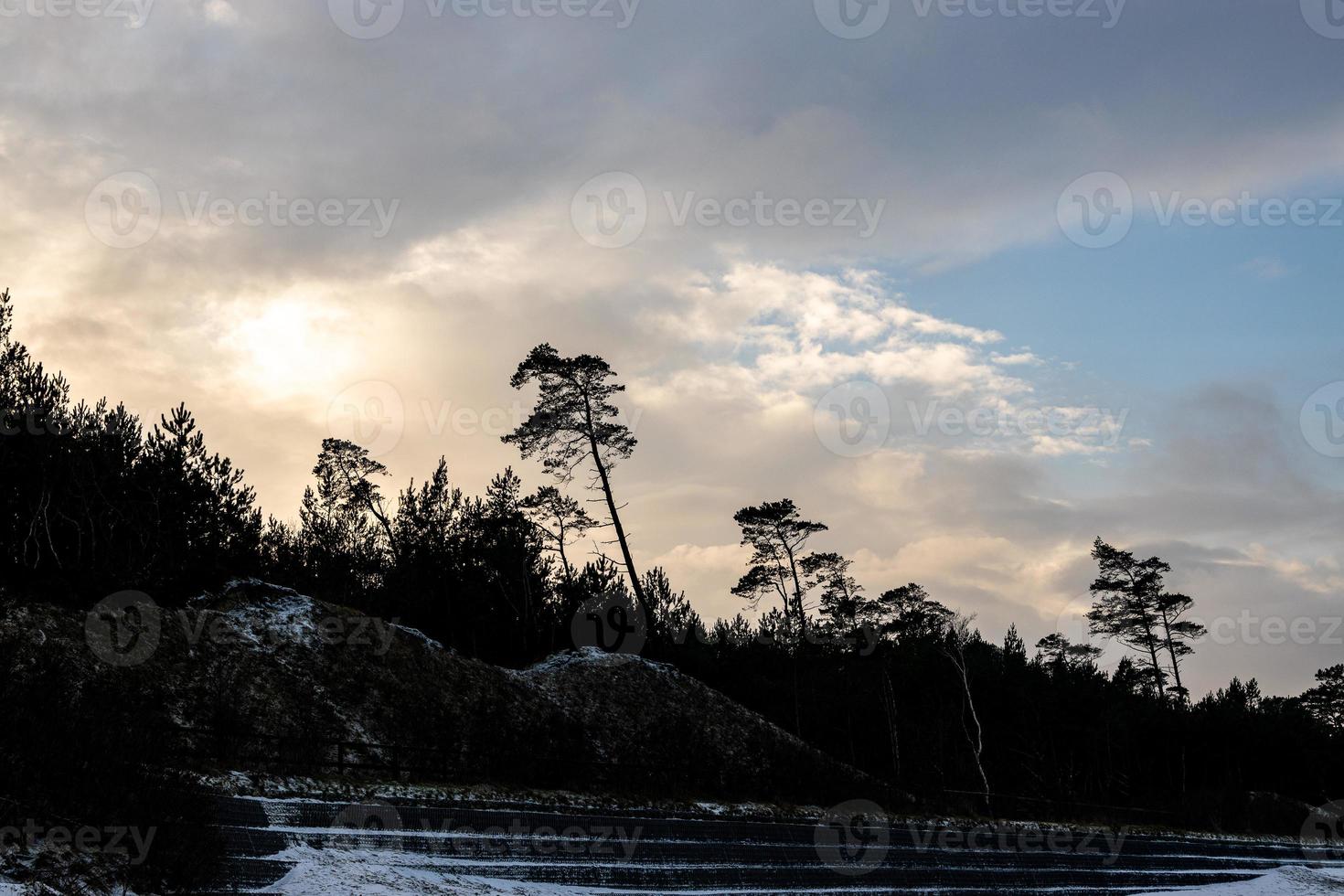 zonsondergang over- de duinen door de Baltisch zee Aan een ijzig winter dag met wolken foto