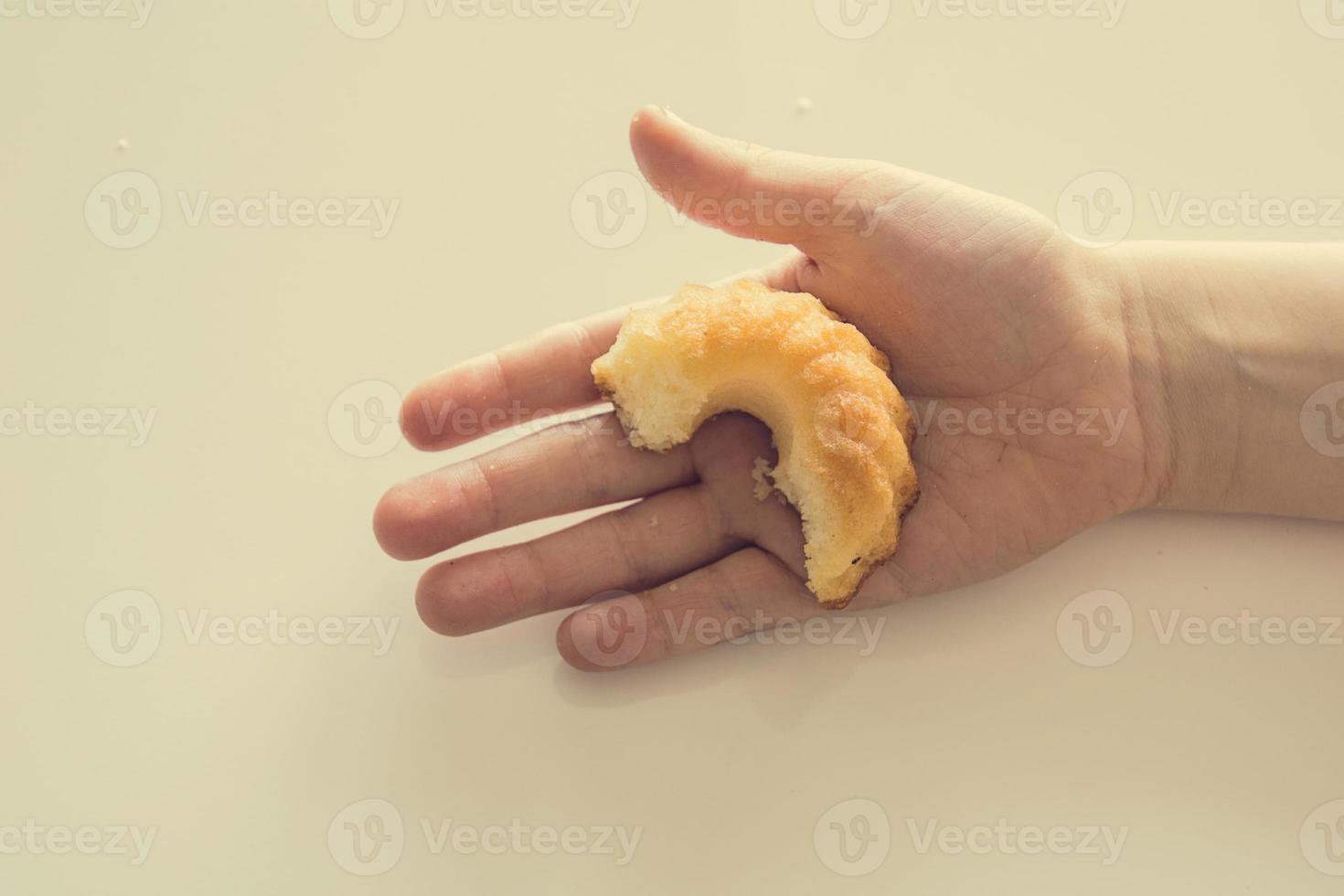 smakelijk weinig Pasen koekje Aan een kind hand- Aan een licht achtergrond foto