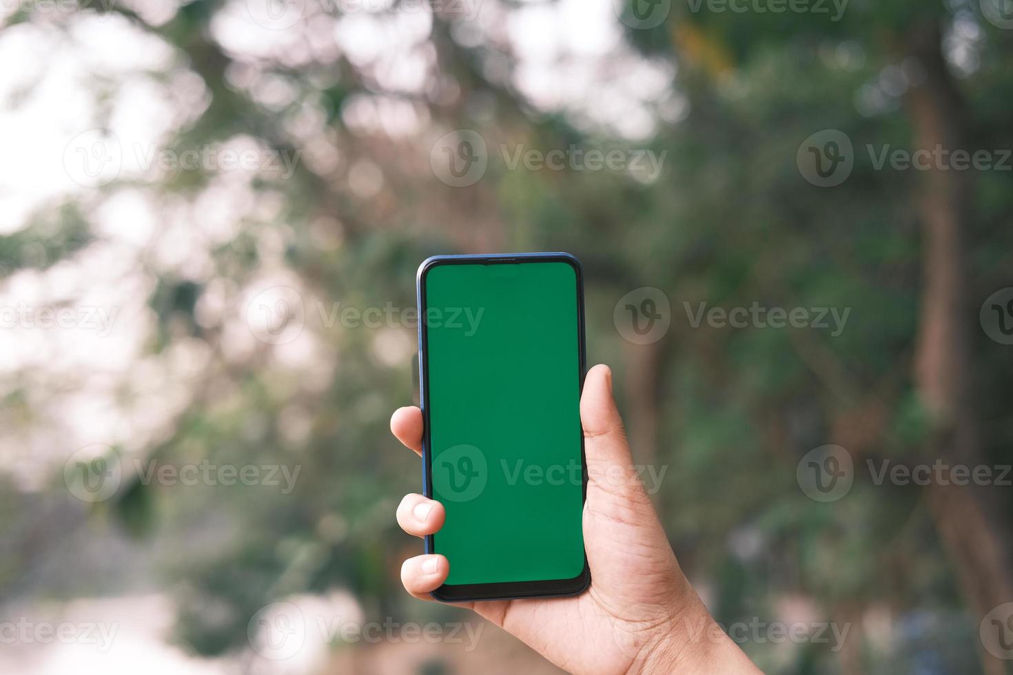 man met telefoon buiten met groen scherm foto