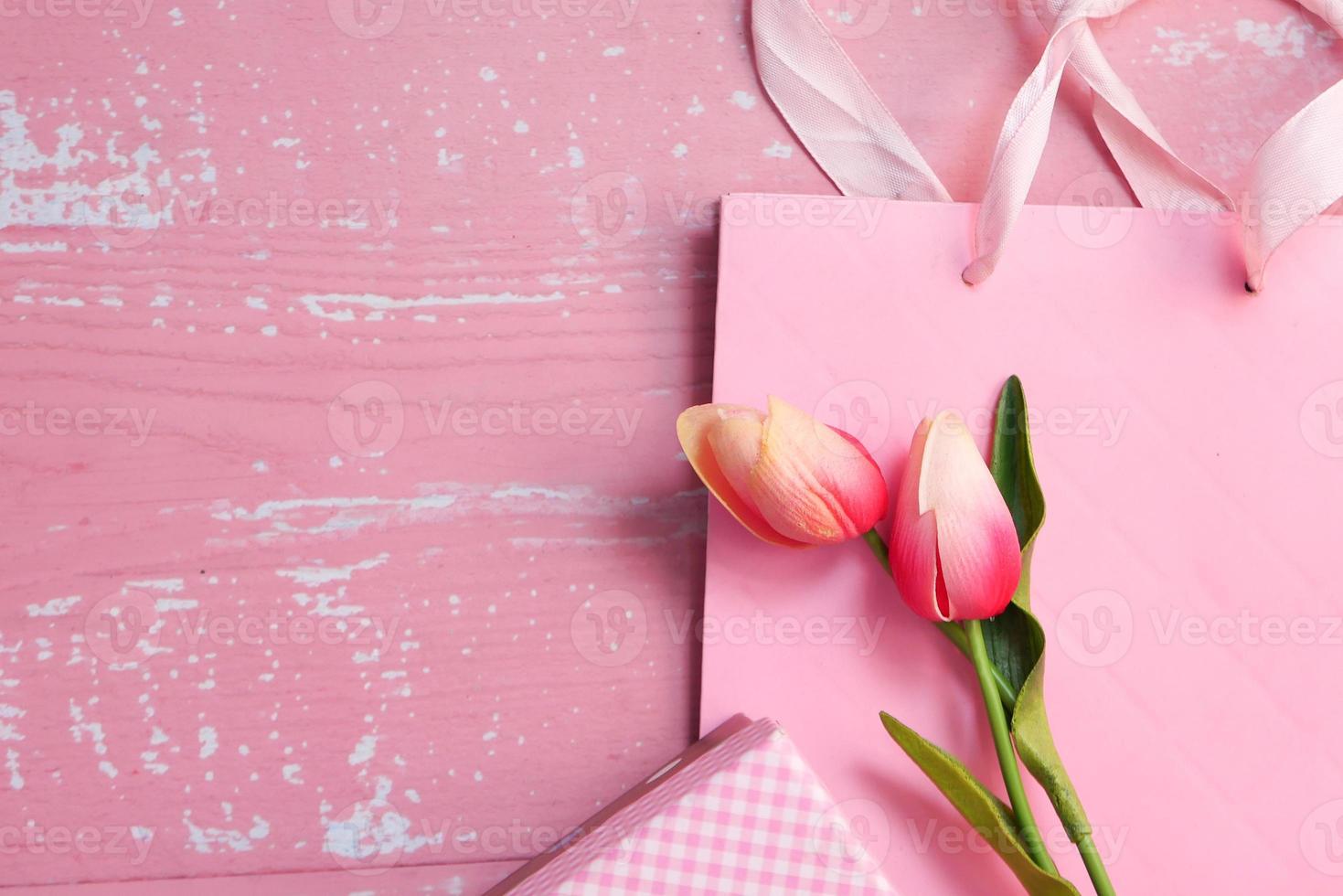 bovenaanzicht van roze kleur cadeauzakje en bloemen foto