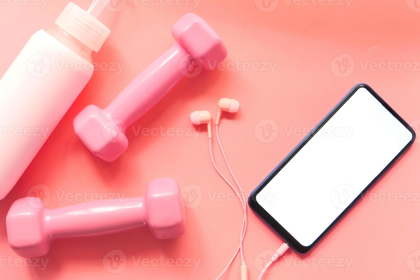 slimme telefoon met roze sportartikelen op houten vloer foto