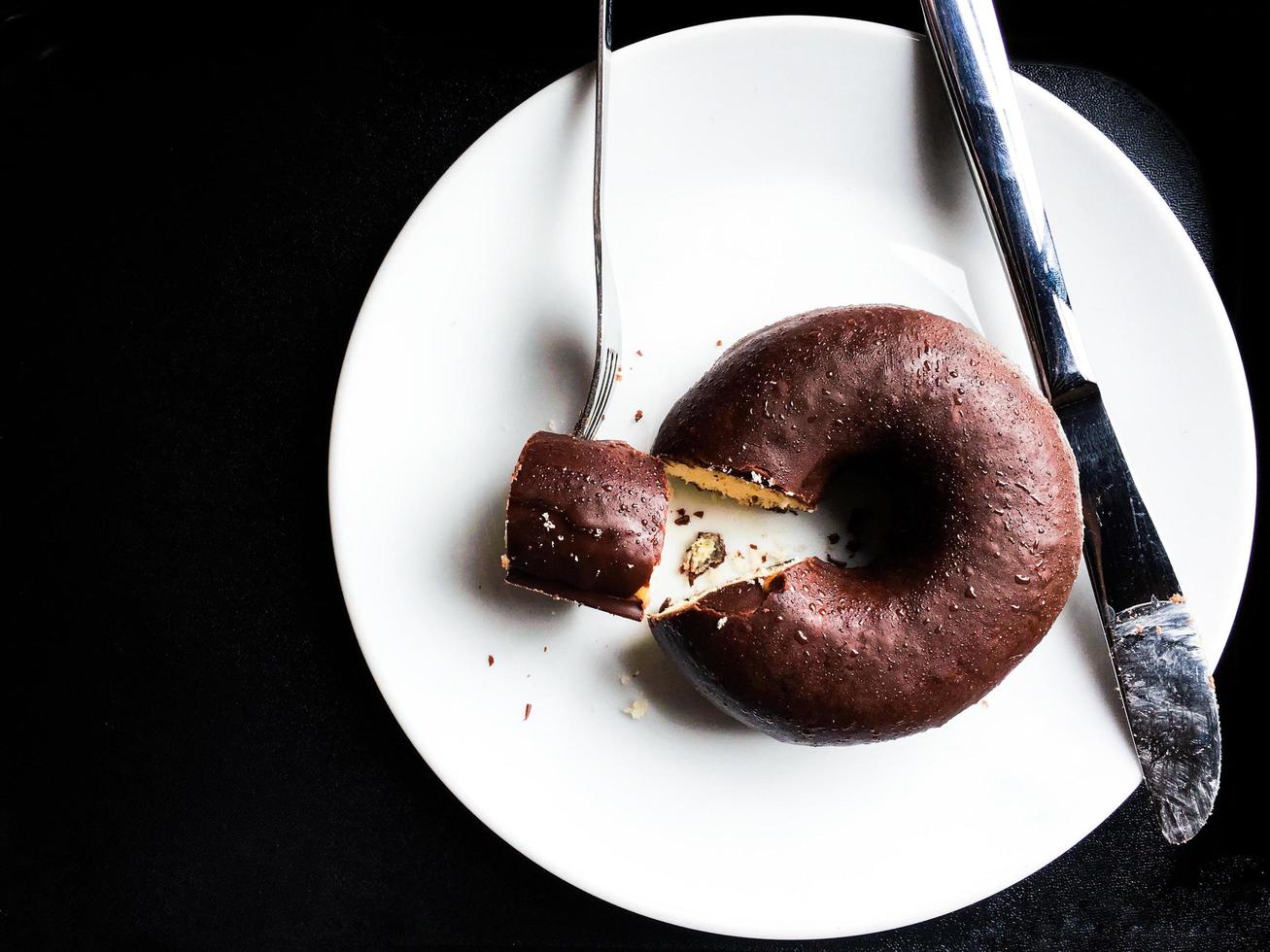chocolade donut op witte schotel op geïsoleerde zwarte achtergrond foto