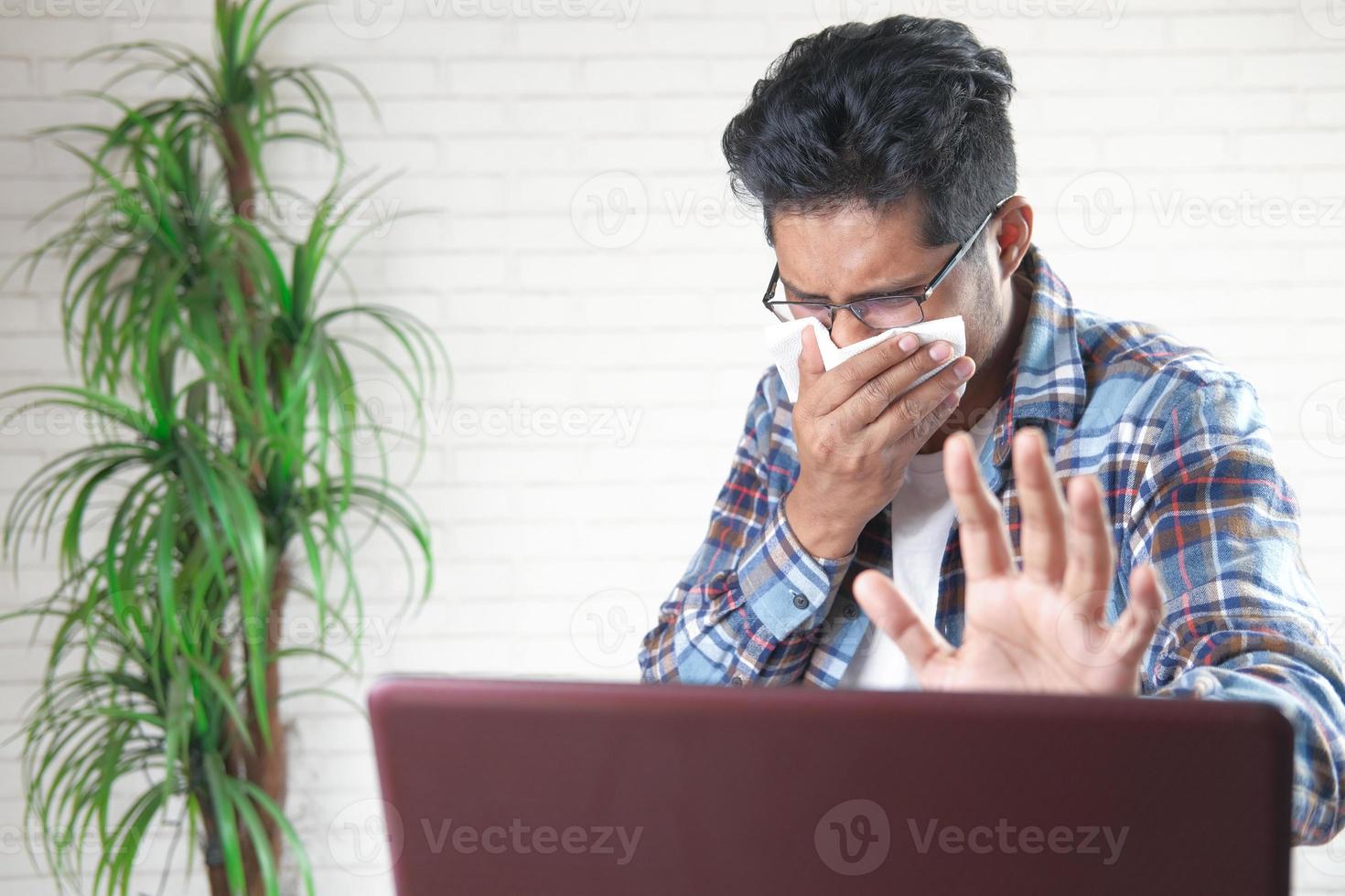 man hoesten en niest bezig met laptop foto