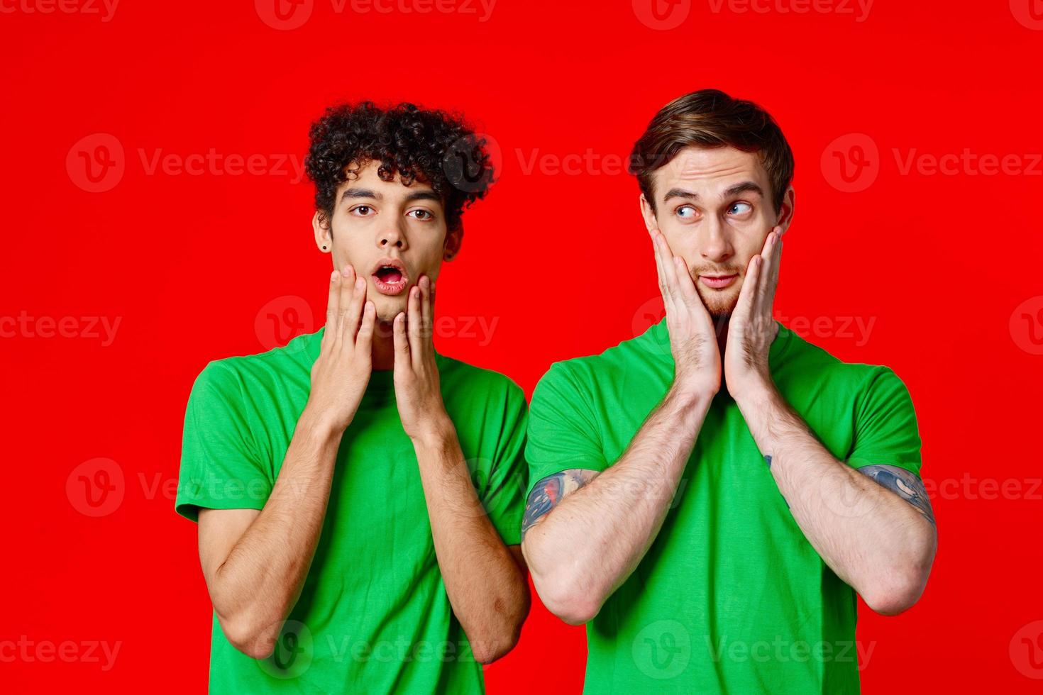 vrolijk vrienden in groen t-shirts houden Aan naar de gezicht van emotie foto