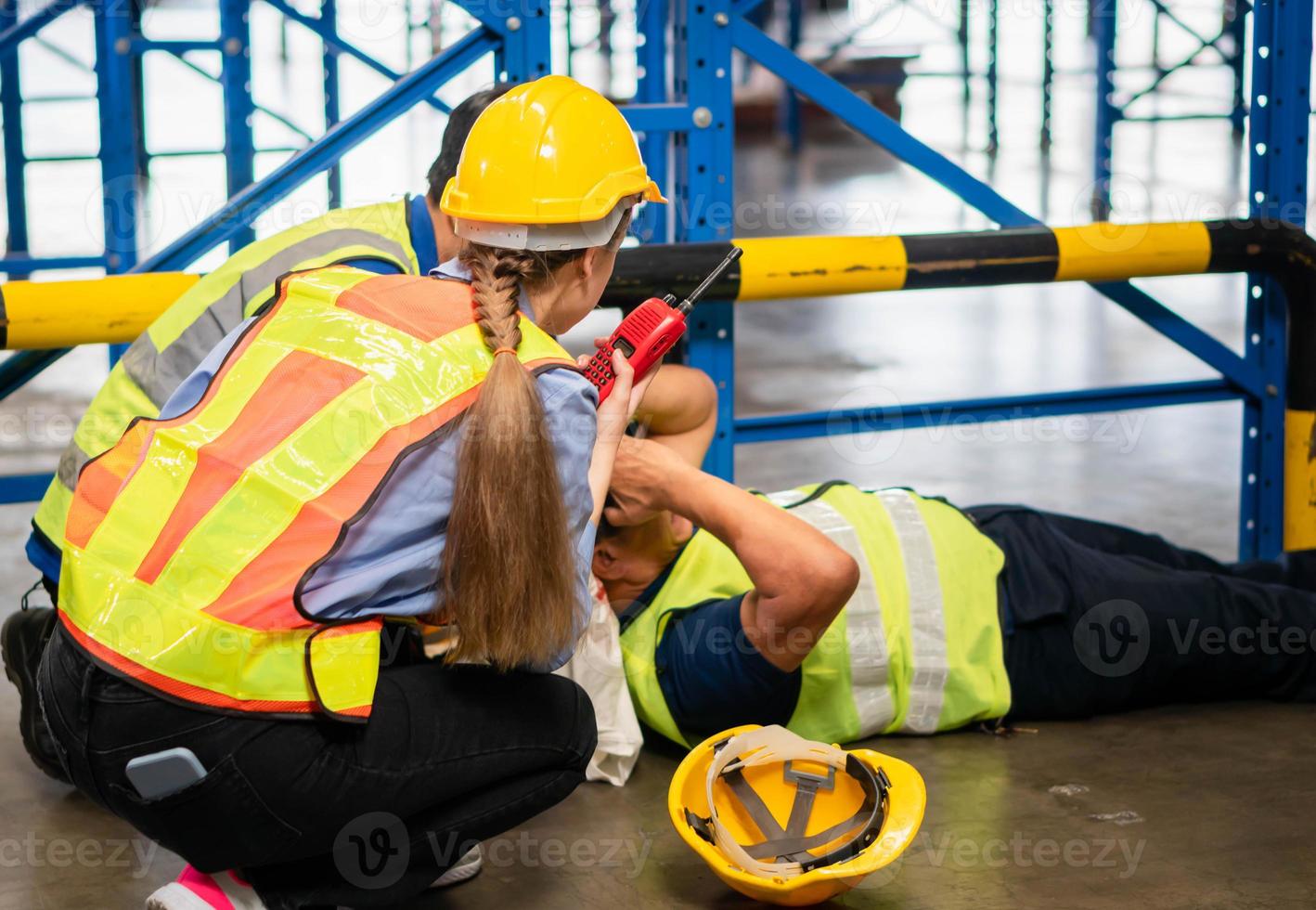 ongeluk Bij werk concepten, voorman arbeiders nemen zorg over hun collega aan het liegen Aan de verdieping in een magazijn foto