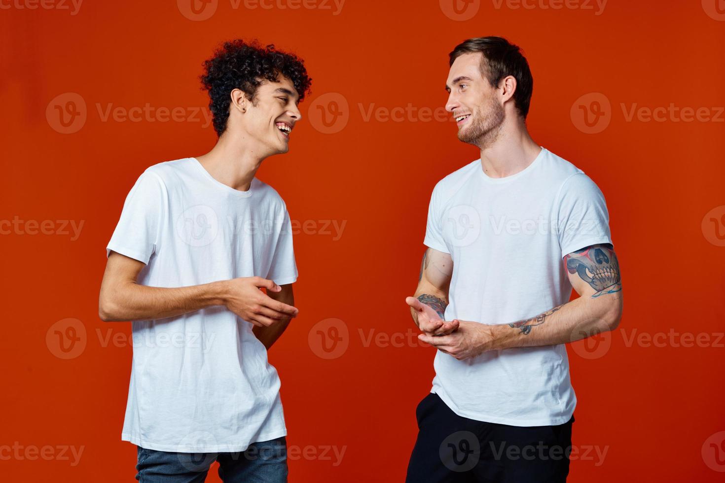 twee vrienden in wit t-shirts knuffels communicatie rood achtergrond foto