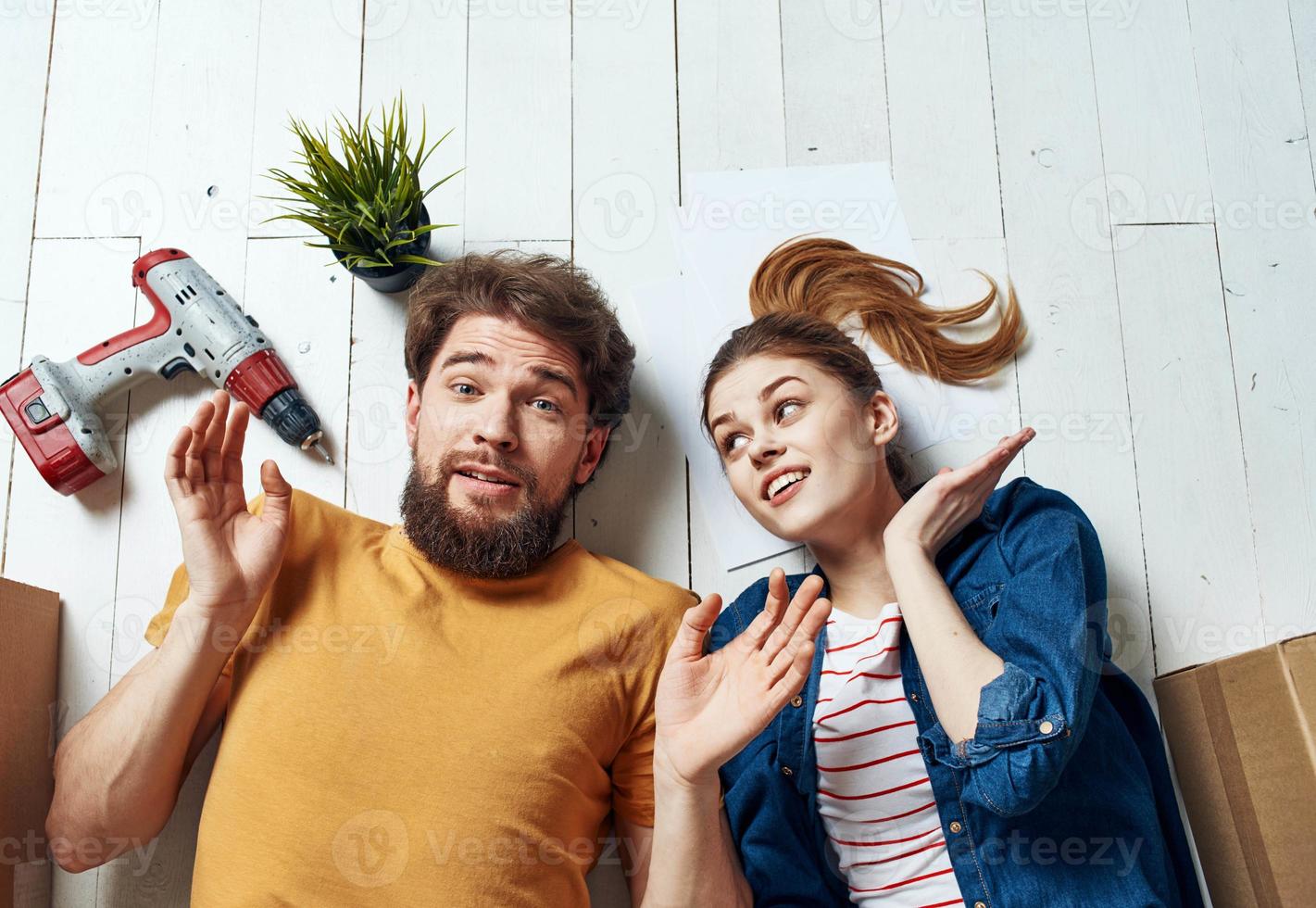 gelukkig Mens en vrouw liggen Aan de verdieping een bloem in een pot planning toekomst vernieuwing werk foto