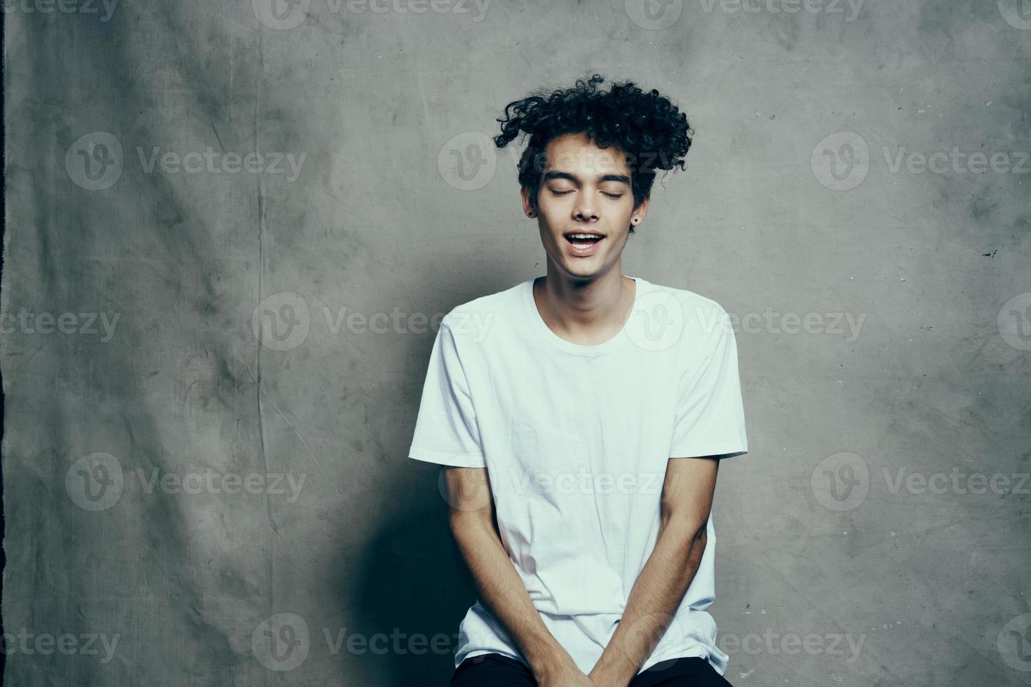 portret van een aantrekkelijk jong Mens in een t-shirt met gekruld haar- detailopname kleding stof achtergrond foto