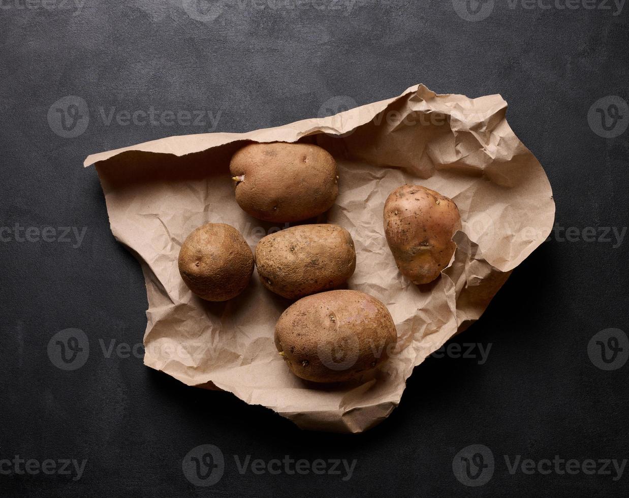 rauw aardappelen liggen Aan een bruin stuk van papier, top visie foto