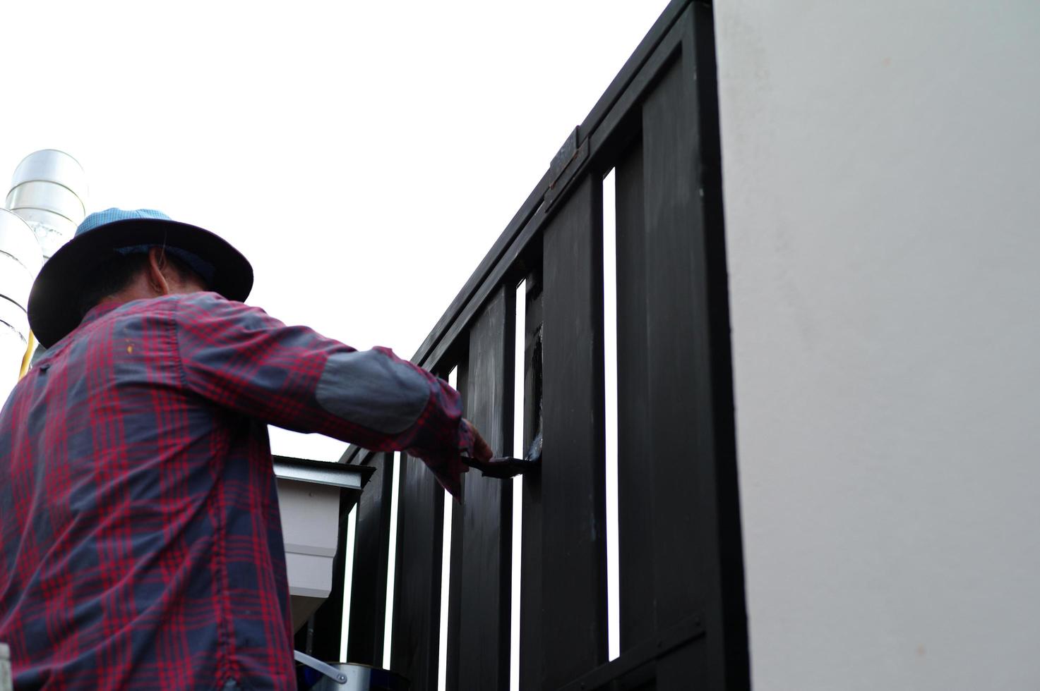 motie wazig hand van werknemer schilderij zwarte kleur op het stalen hek foto