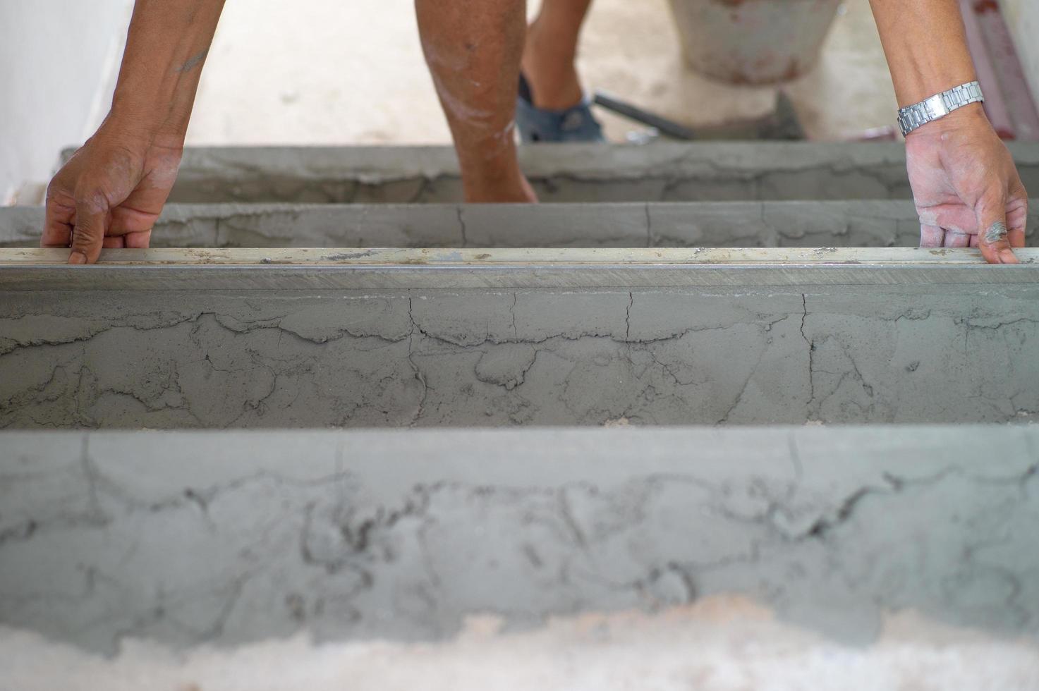close-up handen van werknemer werkt met troffel in gepleisterde cementvloer foto