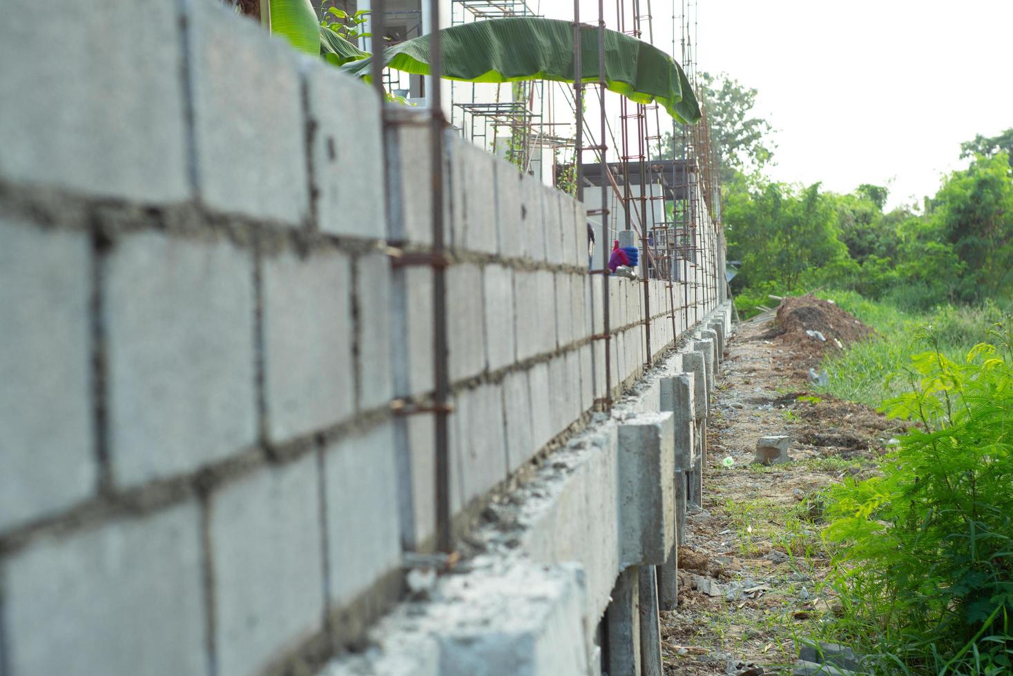 landschap van bouwplaats met betonnen metselaarsmuur en hand van arbeider die de bakstenen op de muur op achtergrond installeert foto