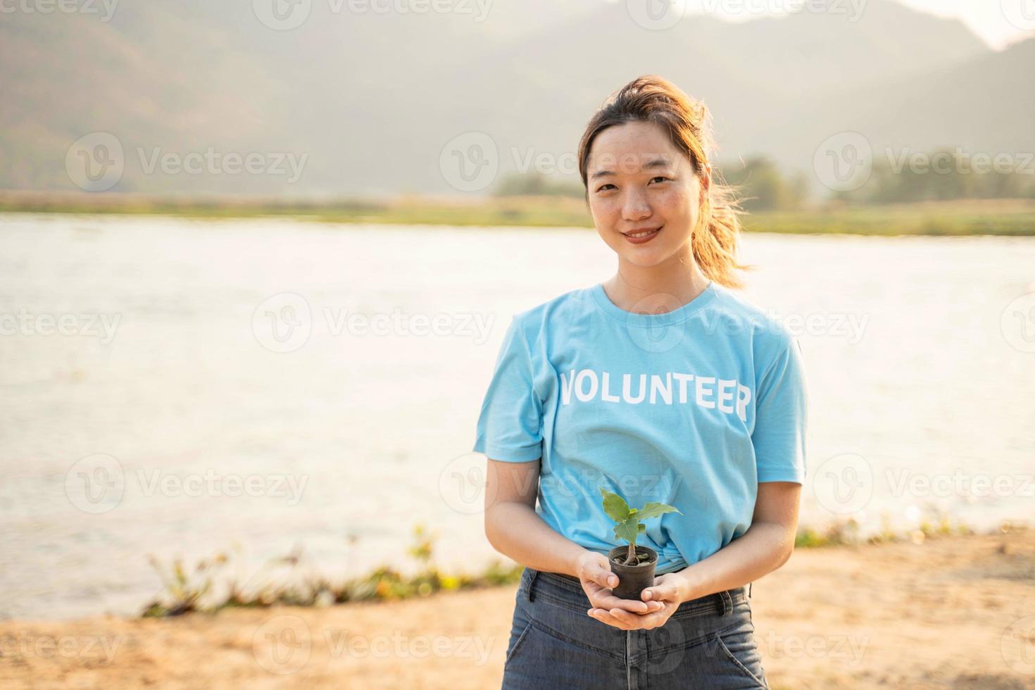 vrouw vrijwilliger draag- een zaailingen naar worden geplant in de bodem in de rivier- net zo opslaan wereld concept, natuur, milieu en ecologie. foto