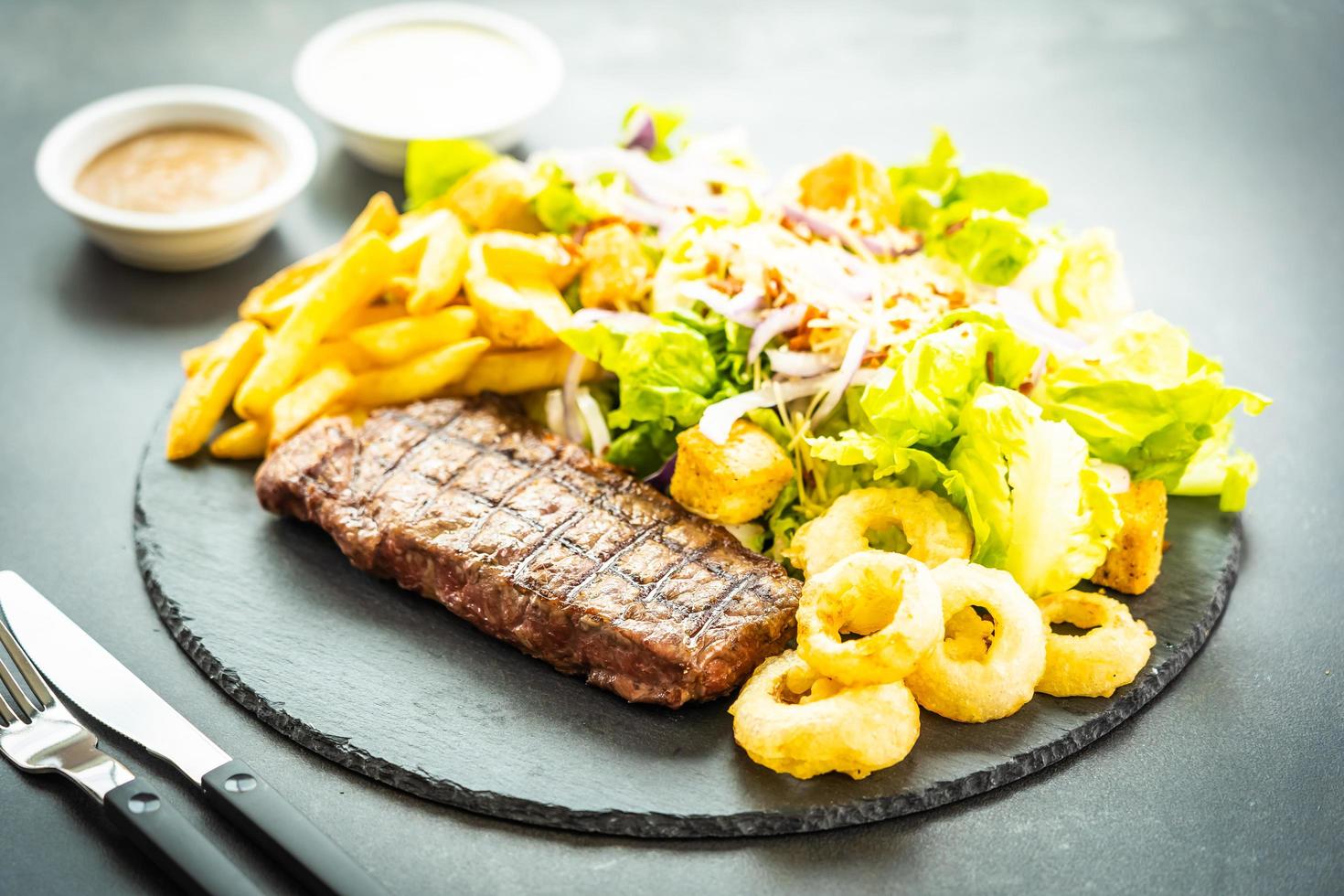 gegrilde biefstuk met frietjes uienring met saus en verse groente foto