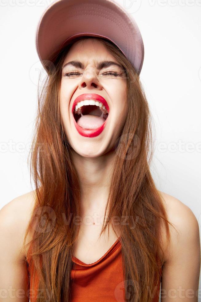 vrouw met een pet met Gesloten ogen opent zijn mond breed emoties Aan haar hoofd rood lippen foto