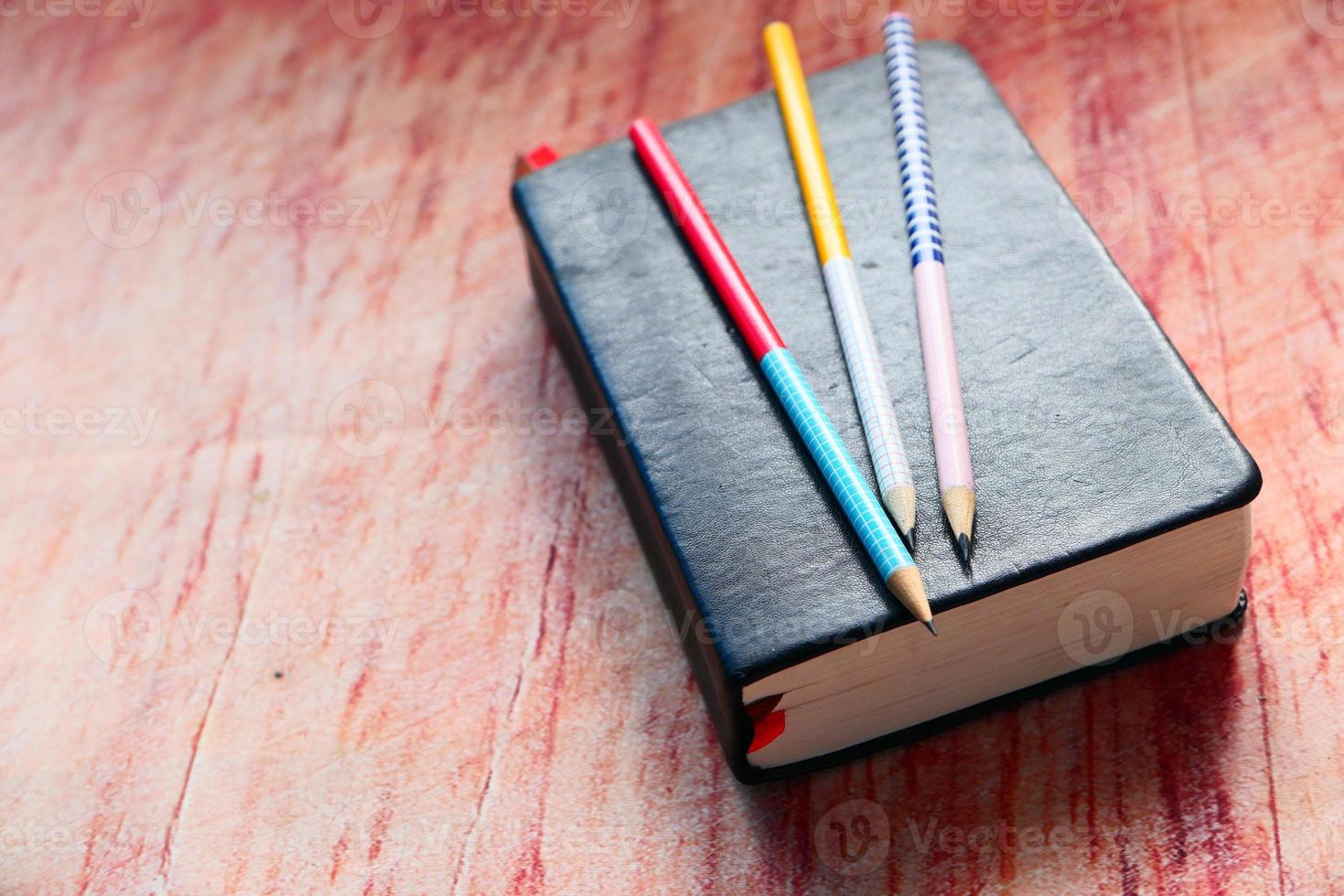 boek met potloden op houten bureau foto