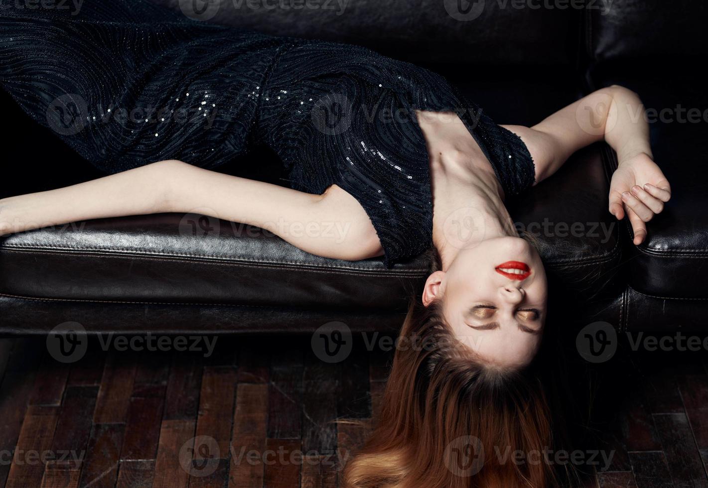 mooi vrouw met helder bedenken leugens Aan een leer sofa detailopname rood haar- model- foto