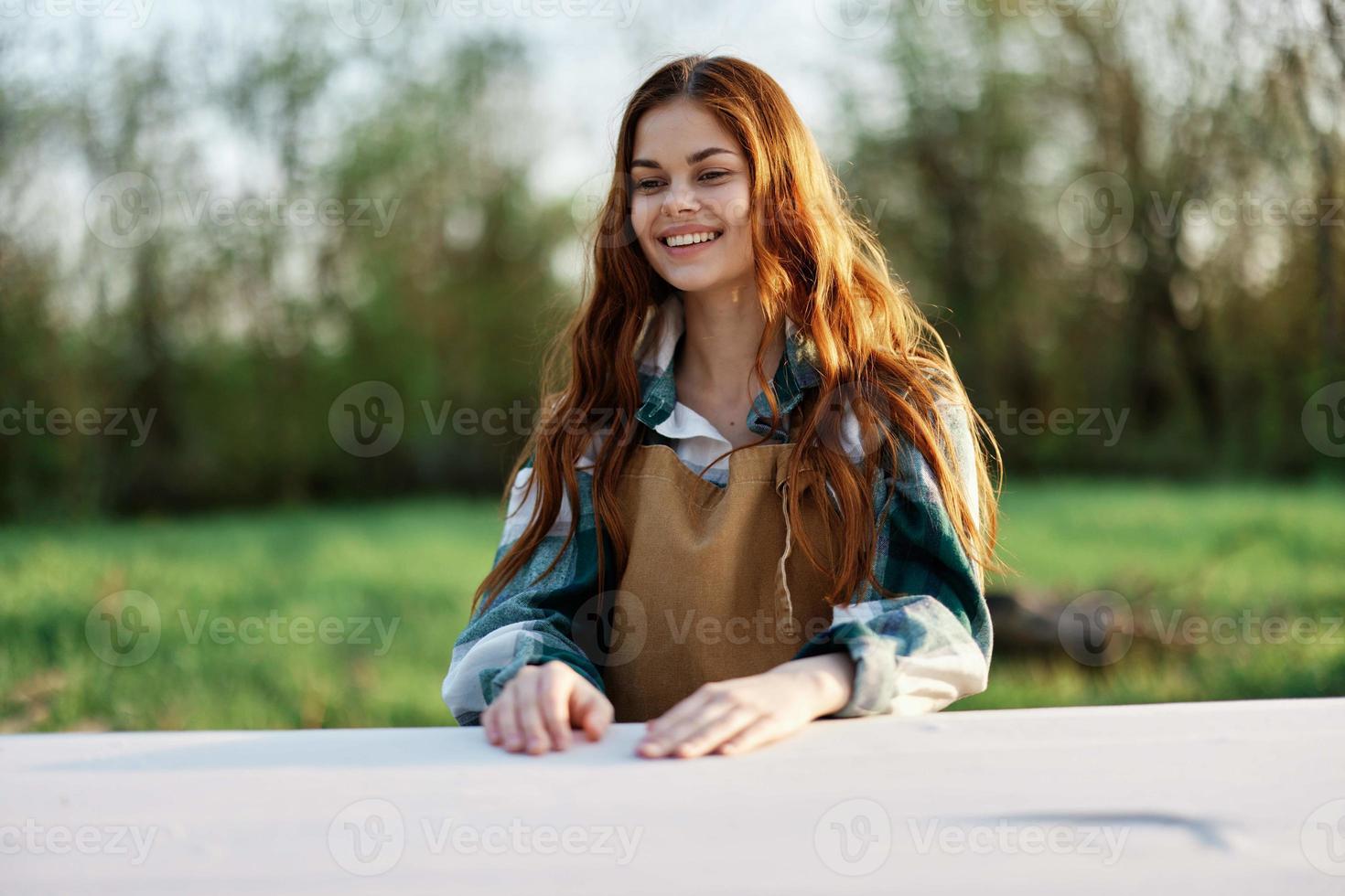 een mooi vrouw lacht met een toothy glimlach en geniet loungen in een groen park Aan een zomer avond in de instelling zonlicht. de concept van een gezond levensstijl en de bati van zelfzorg foto