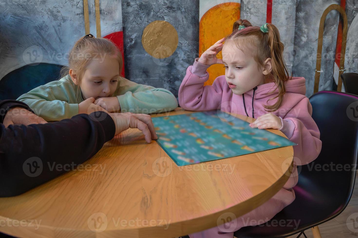 een familie met kinderen zitten in een cafe en studie de menu voor bestellen voedsel. foto