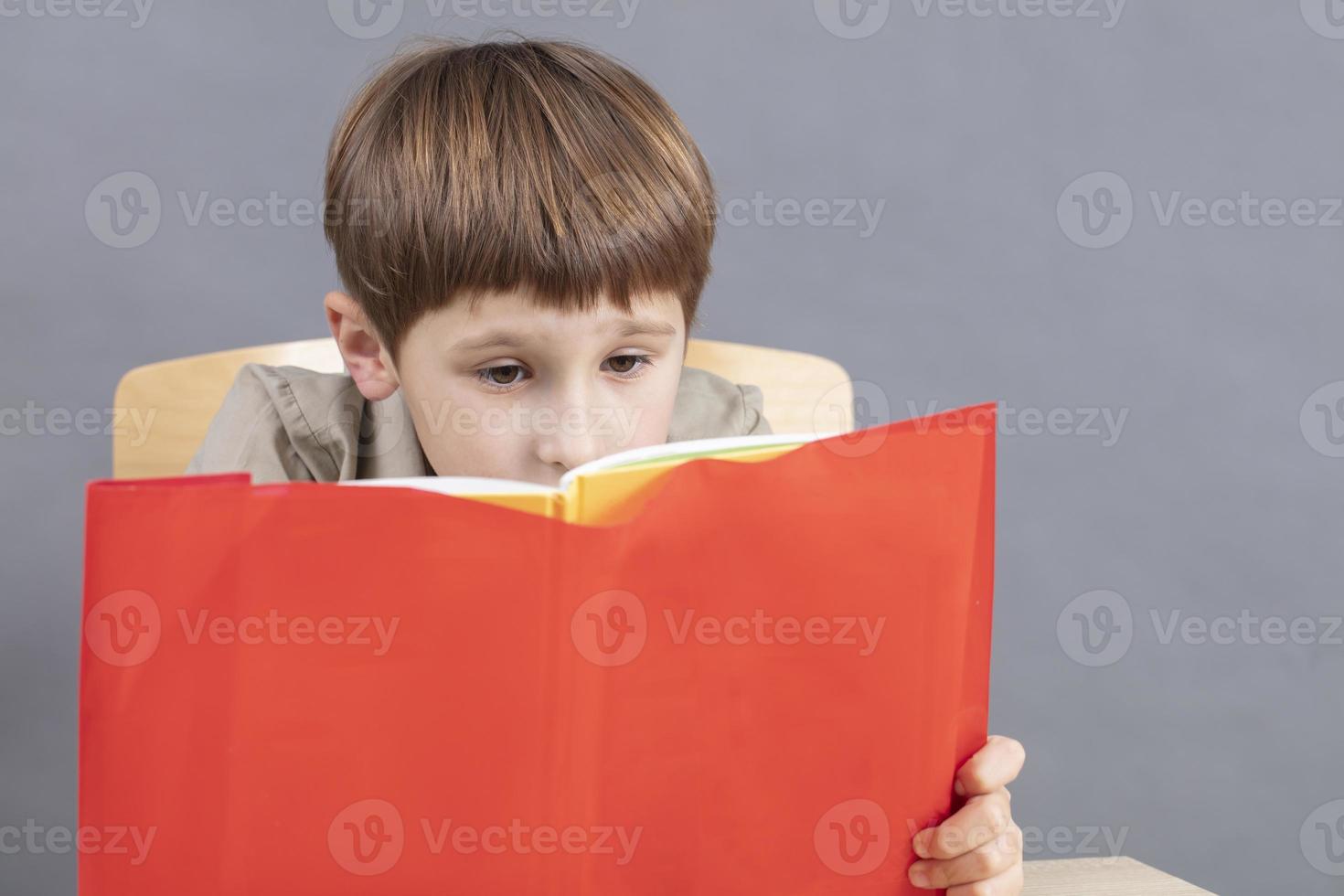 de kind Bij de tafel is aan het doen huiswerk. een primair school- leerling leest een leerboek. foto