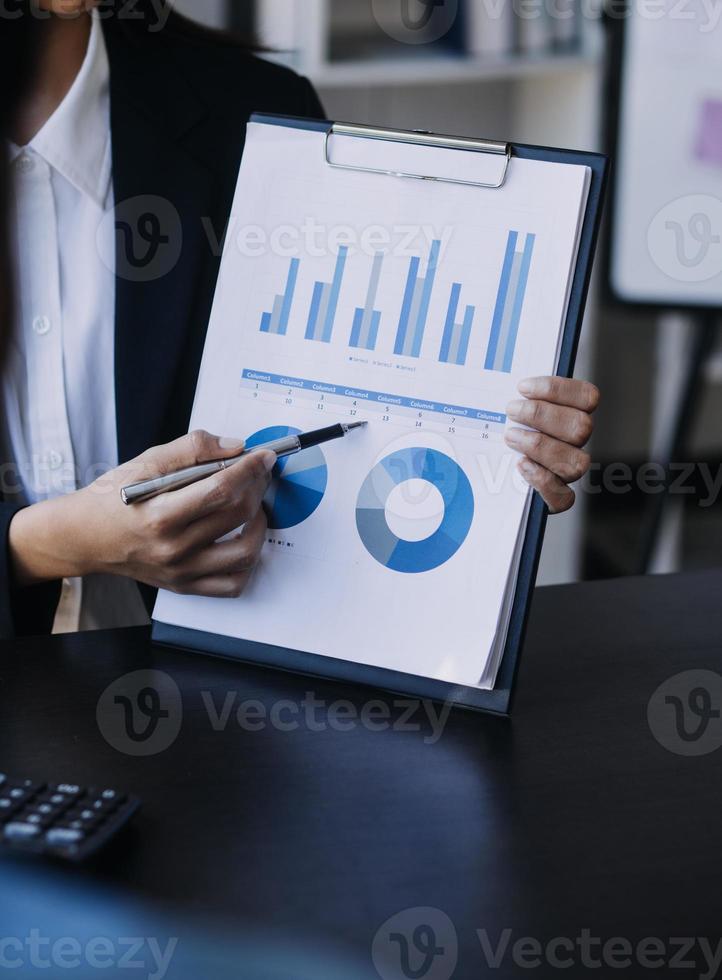 Aziatisch bedrijf vrouw gebruik makend van rekenmachine en laptop voor aan het doen wiskunde financiën Aan een kantoor bureau, belasting, rapport, boekhouding, statistieken, en analytisch Onderzoek concept foto