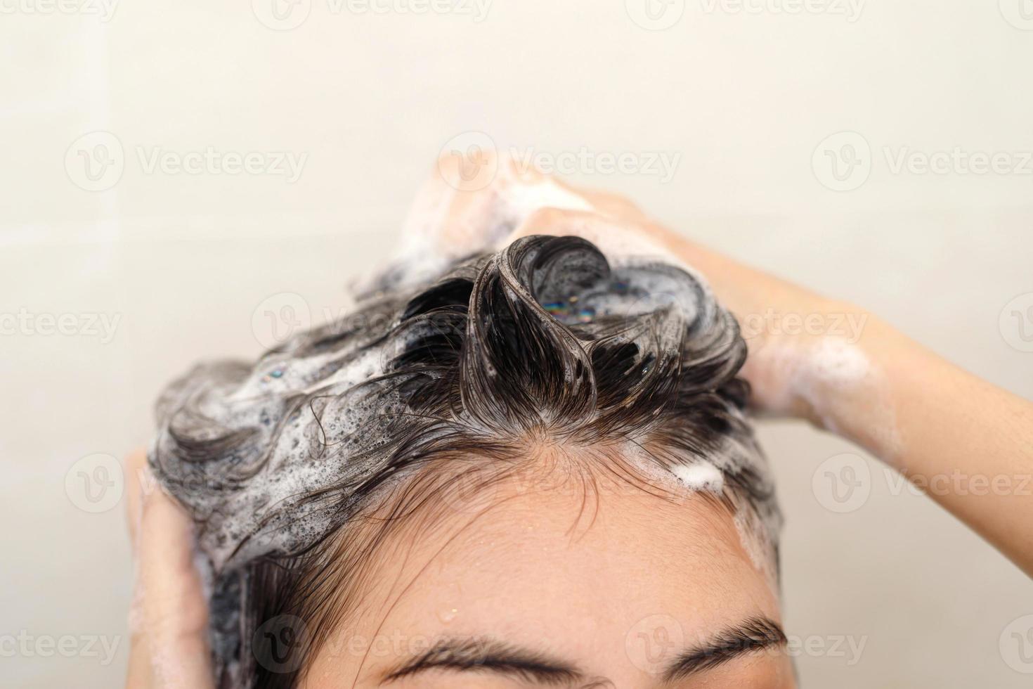 vrouw nemen douche en het wassen haar- met shampoo in badkamer Bij huis foto