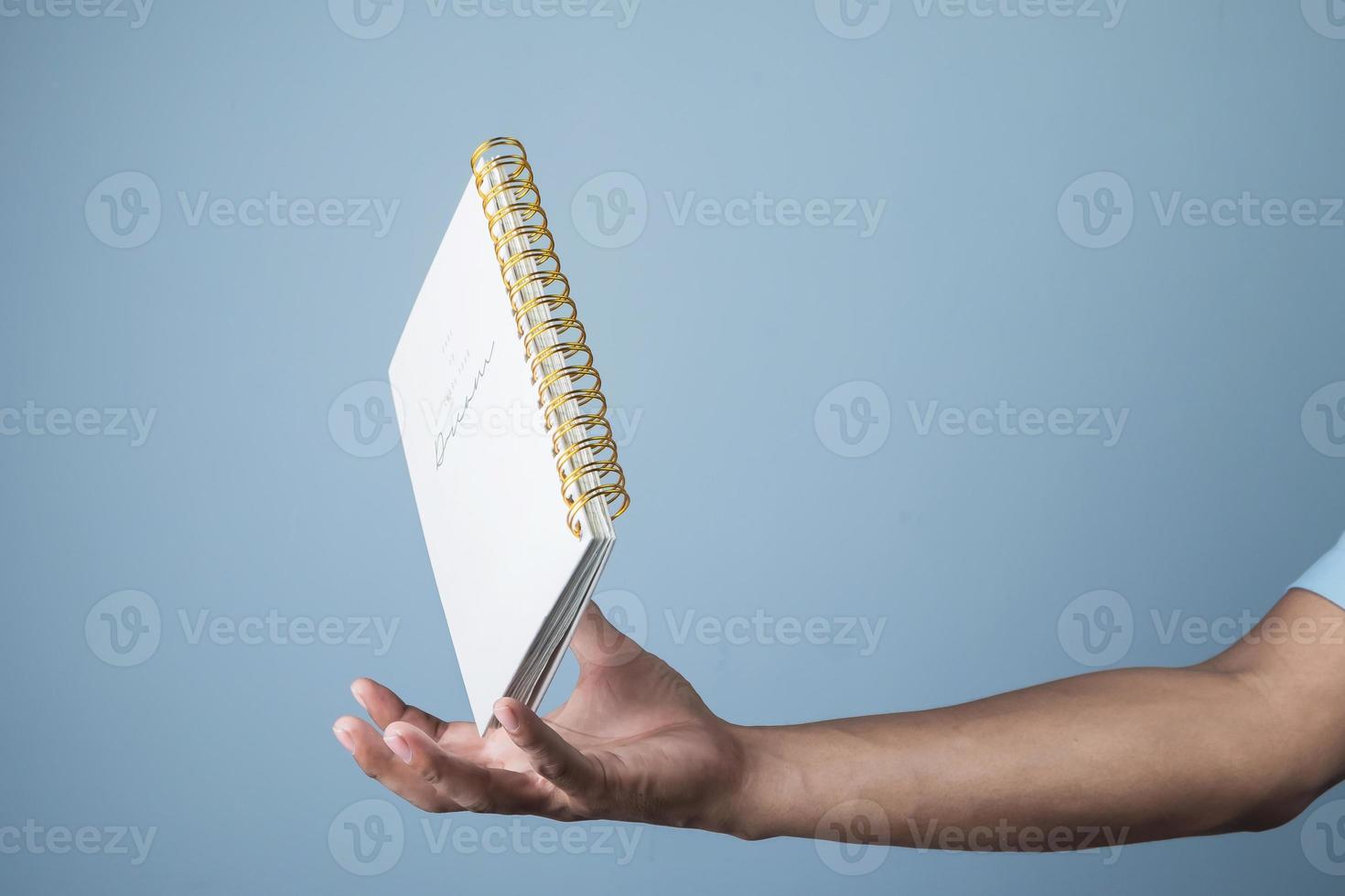 blanco kladblok zweven over- zakenman hand- Aan licht blauw achtergrond, kopiëren ruimte voor uw tekst foto