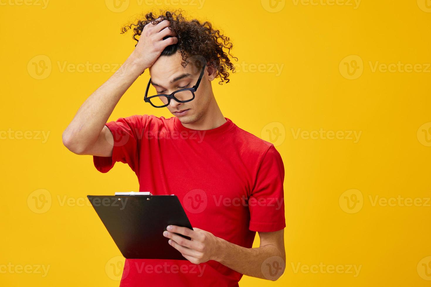 attent kortzichtig jong leerling Mens in rood t-shirt grappig eyewear houdt tablet map met studie aantekeningen poseren geïsoleerd Aan over- geel studio achtergrond. vrij plaats voor advertentie. onderwijs college concept foto