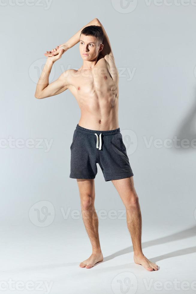 atleet in shorts met een naakt torso toegetreden handen achter de hoofd foto