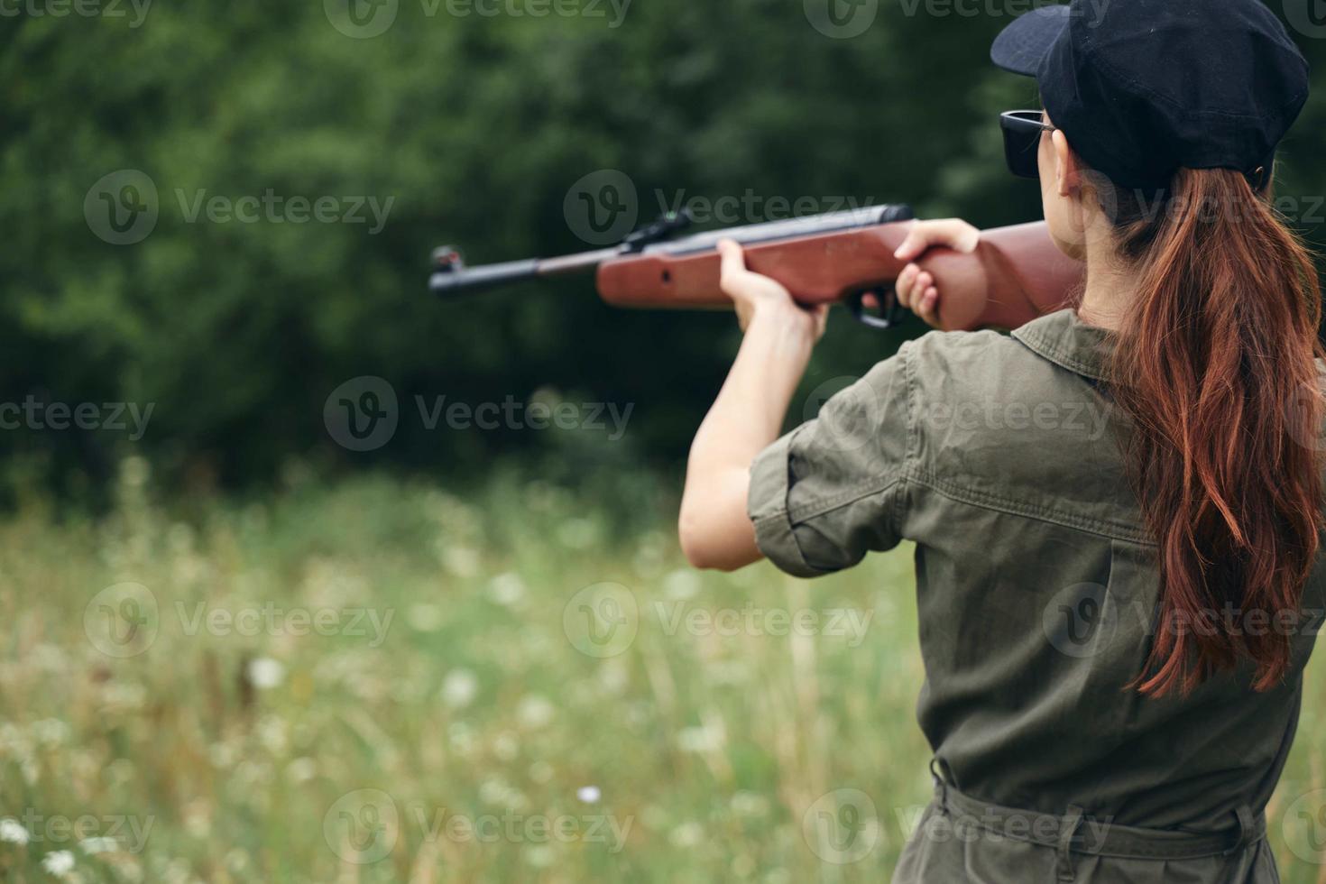 vrouw soldaat Holding wapen in hand- het richten jacht- wapens groen bomen foto