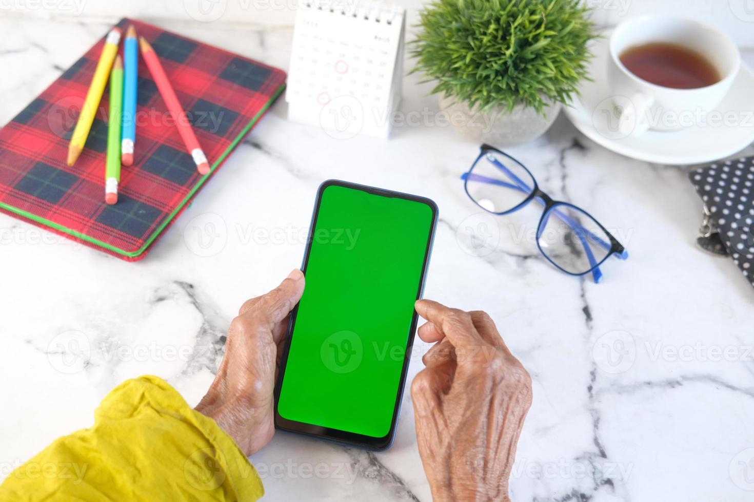 senior vrouwen hand met behulp van slimme telefoon met groen scherm foto