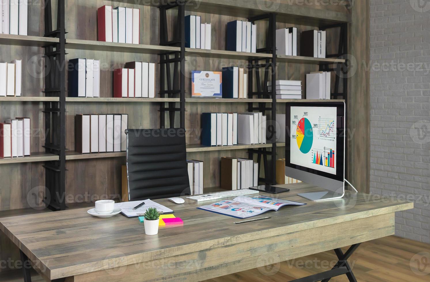 werkruimte met bureaublad computer Aan houten bureau en zwart stoel met boekenplank Aan de achtergrond foto