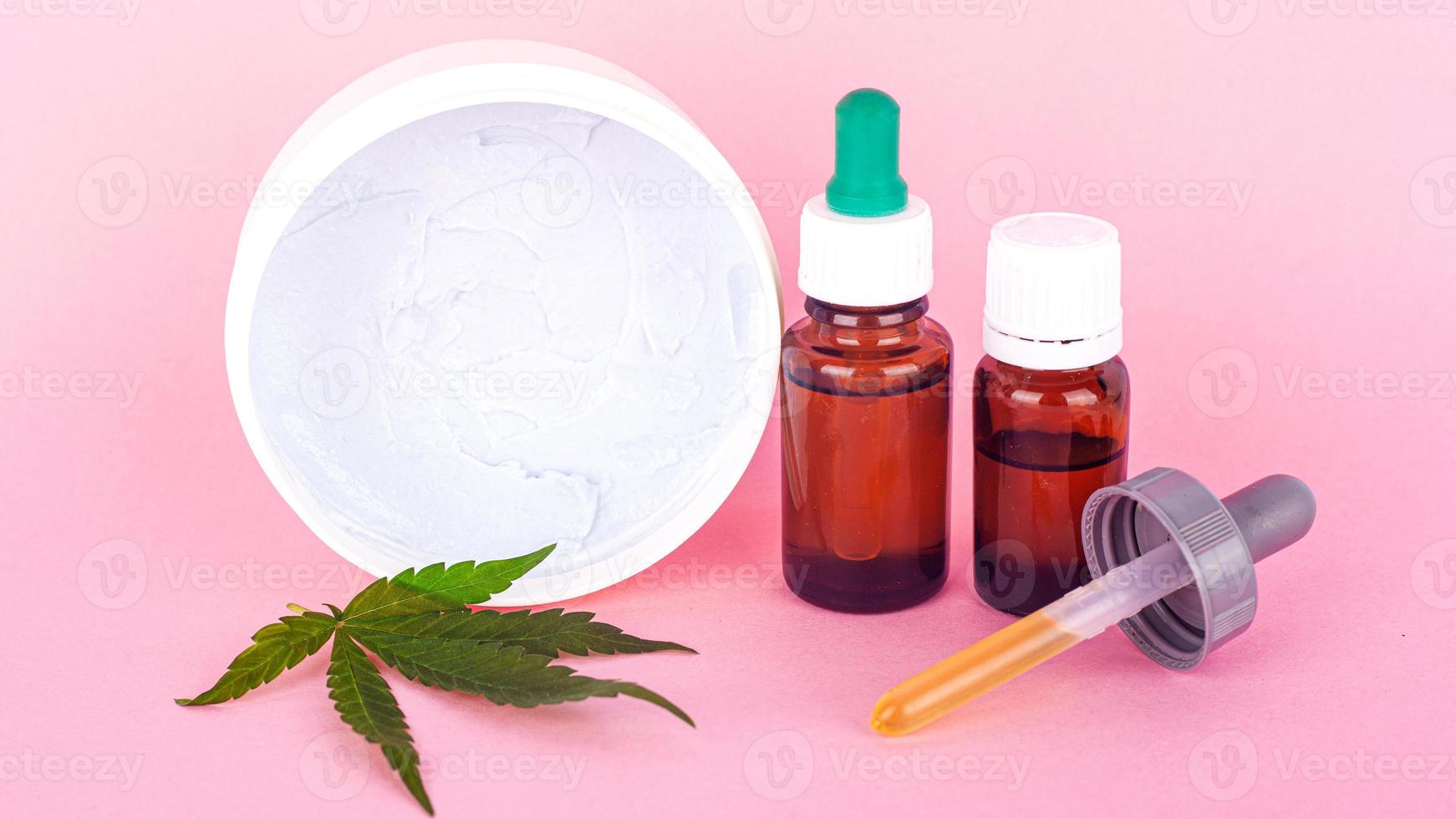 biologische lichaams- en handcrème van marihuana-extract op een roze achtergrond foto