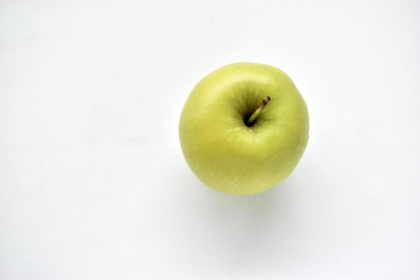 een heldergroene appel op een witte achtergrond foto