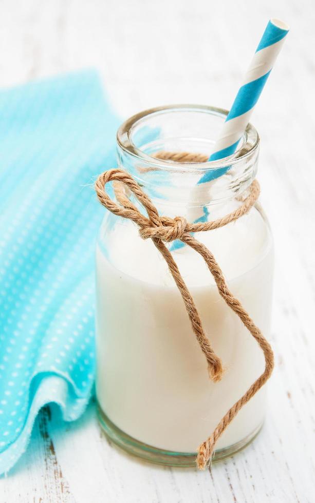 fles melk met een rietje op een houten achtergrond foto