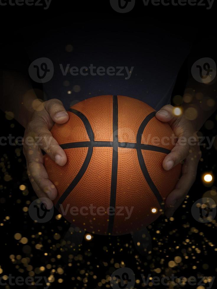 basketbal bal in mannetje handen Aan zwart achtergrond met abstract lichten foto