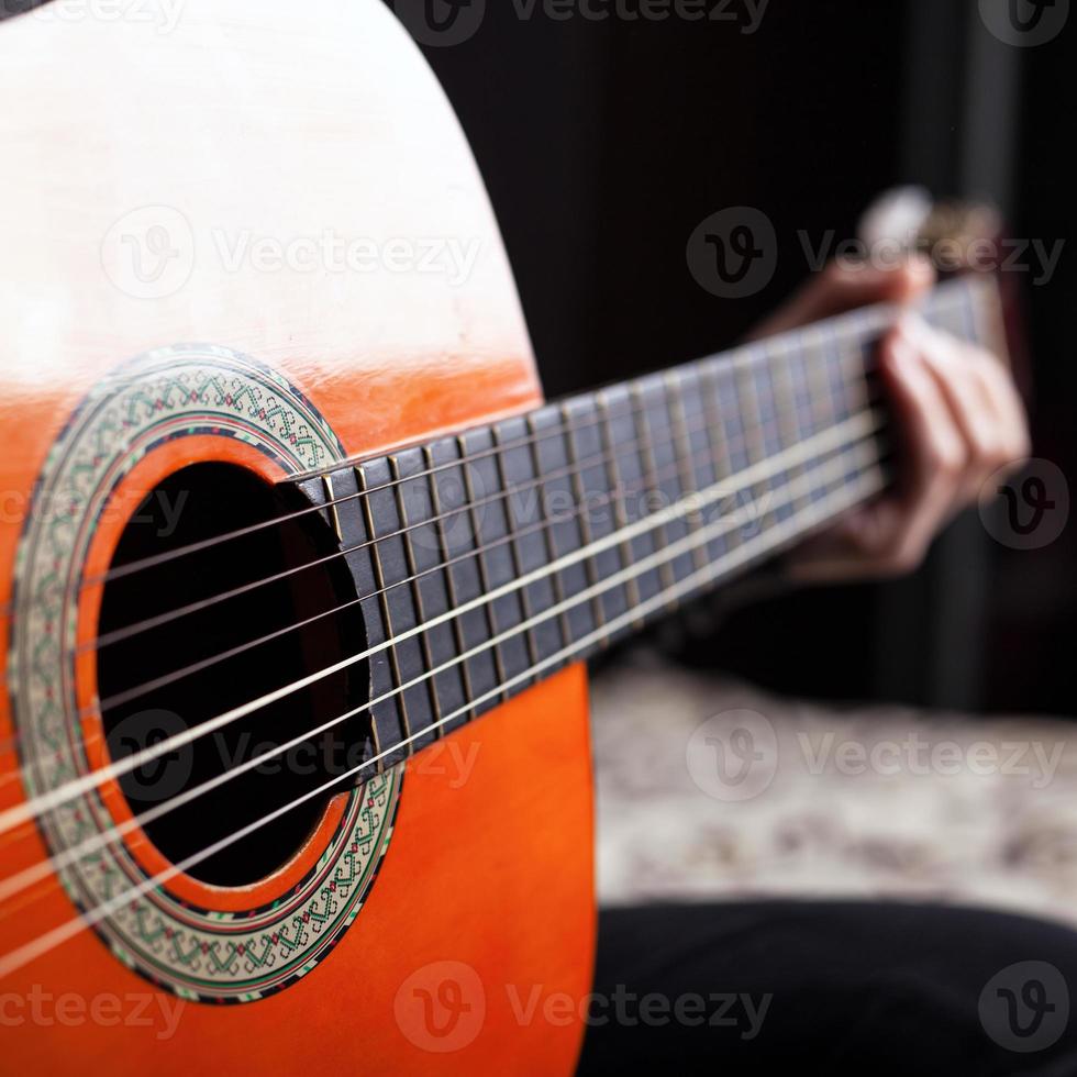 hand op toets van akoestische gitaar in oranje kleur foto