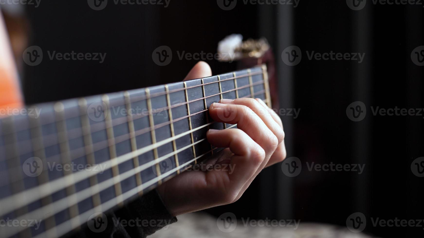 vrouwelijke hand houdt een akkoord op een akoestische gitaar foto