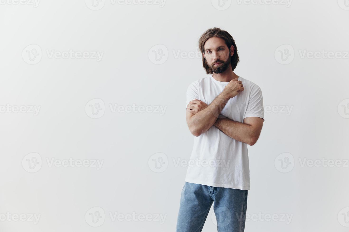 portret van een Mens met een zwart dik baard en lang haar- in een wit t-shirt Aan een wit geïsoleerd achtergrond emotie van droefheid en verlangen foto